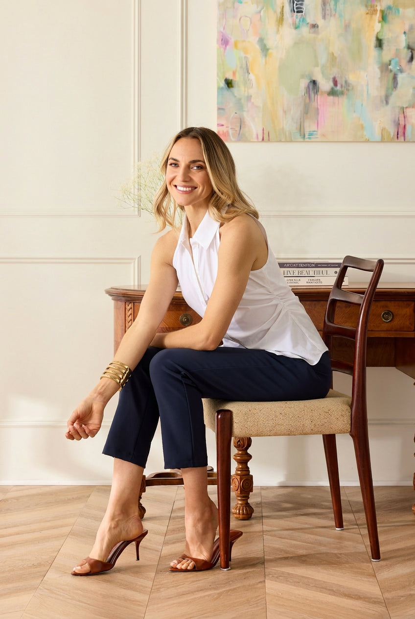 Woman sitting on a chair in a room with a desk and artwork on the wall.