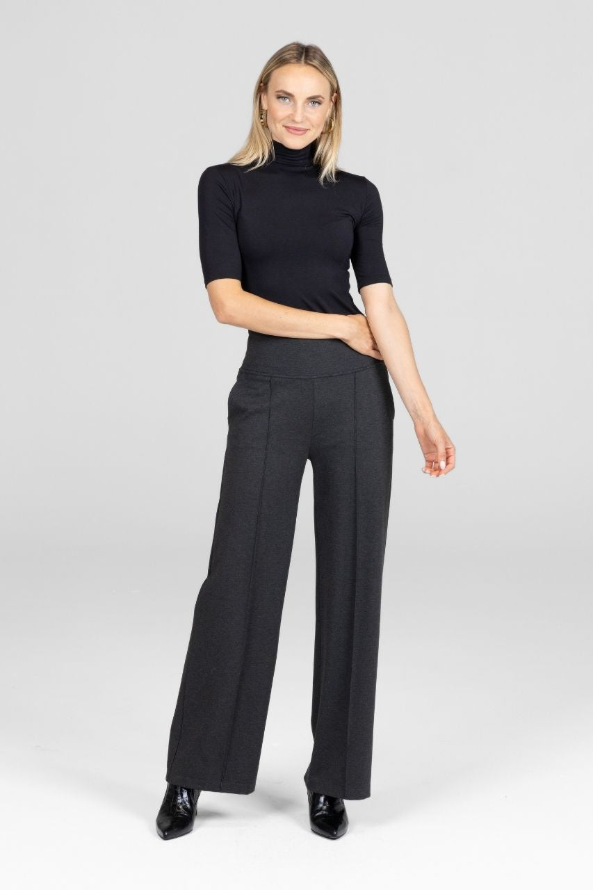Woman wearing a black turtleneck and gray wide-leg pants on a white background