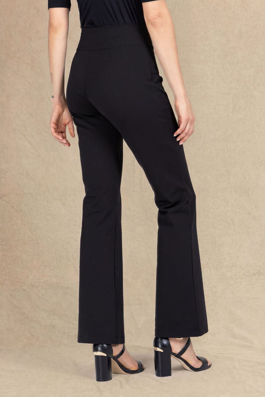 A model shown from the back wearing black high-waisted flared pants and black block-heel sandals against a textured beige studio backdrop.