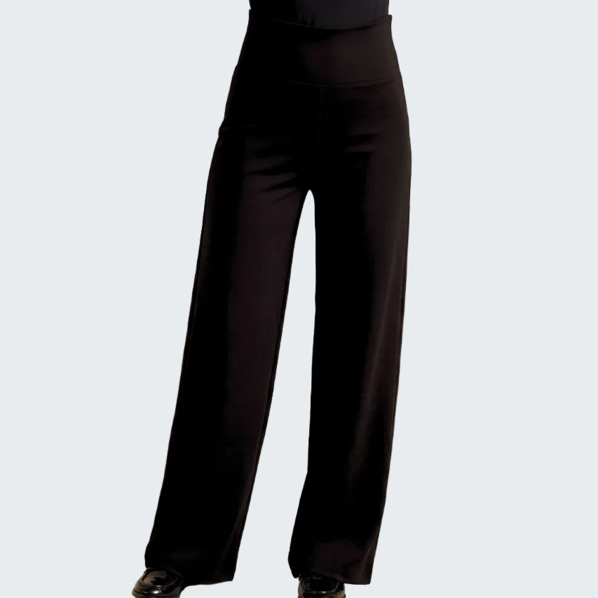 Black wide-leg trousers shown on a model from the waist down, paired with black shoes, against a neutral beige backdrop.