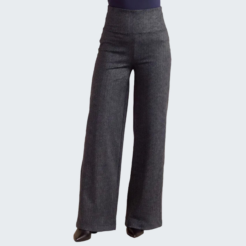 Dark charcoal gray wide-leg trousers shown on a model from the waist down, paired with a navy top and black pointed-toe heels, against a neutral beige backdrop.