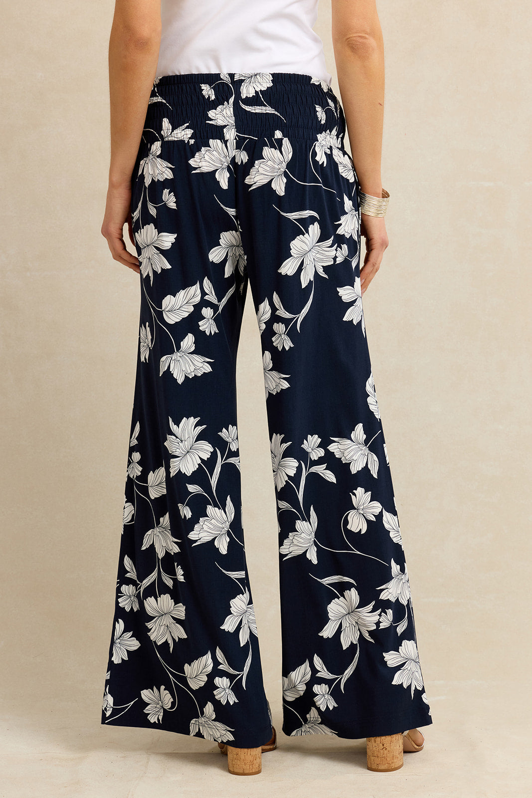 Navy blue pants with white floral pattern worn by a person on a beige background