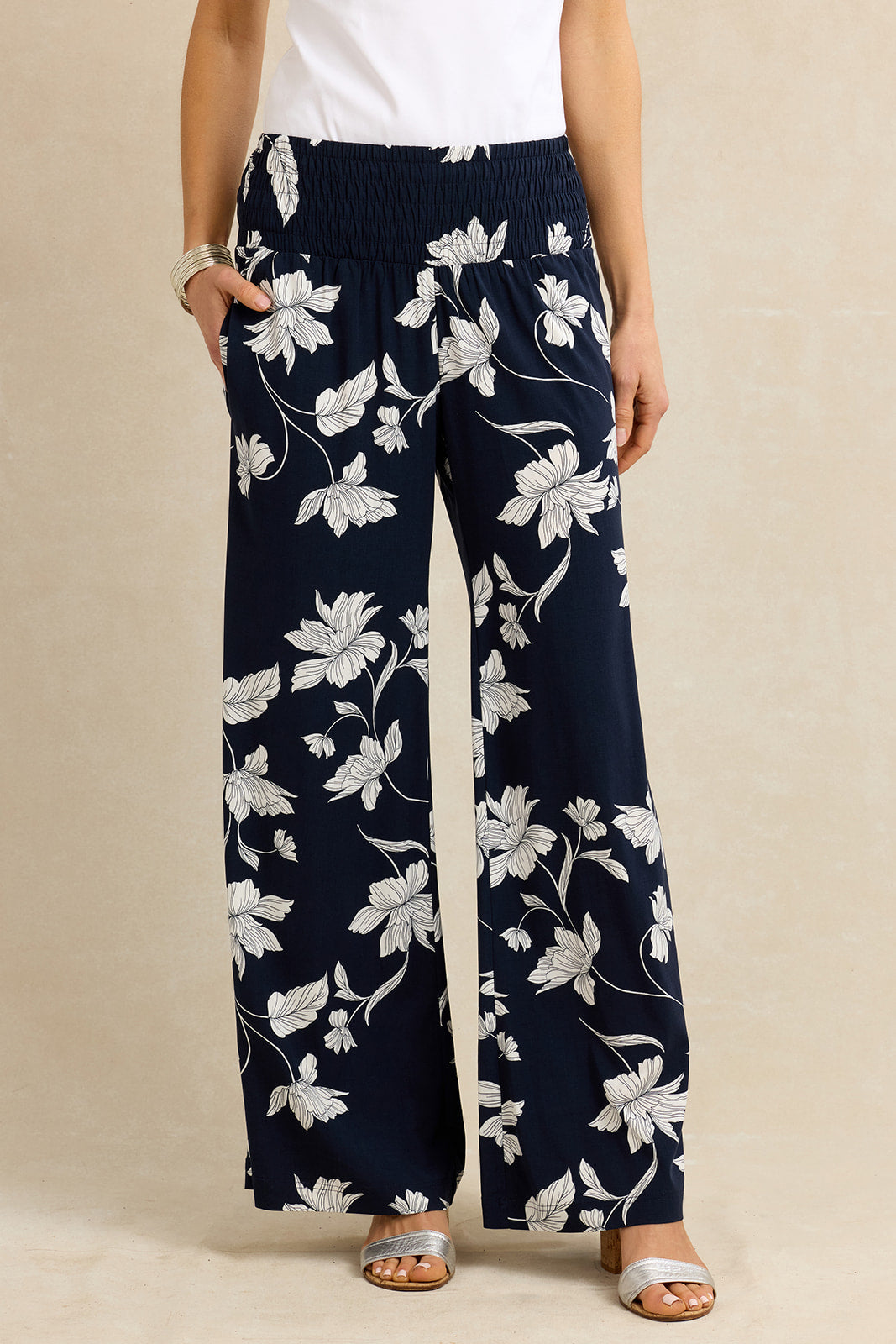 Navy blue pants with white floral pattern worn by a person on a beige background