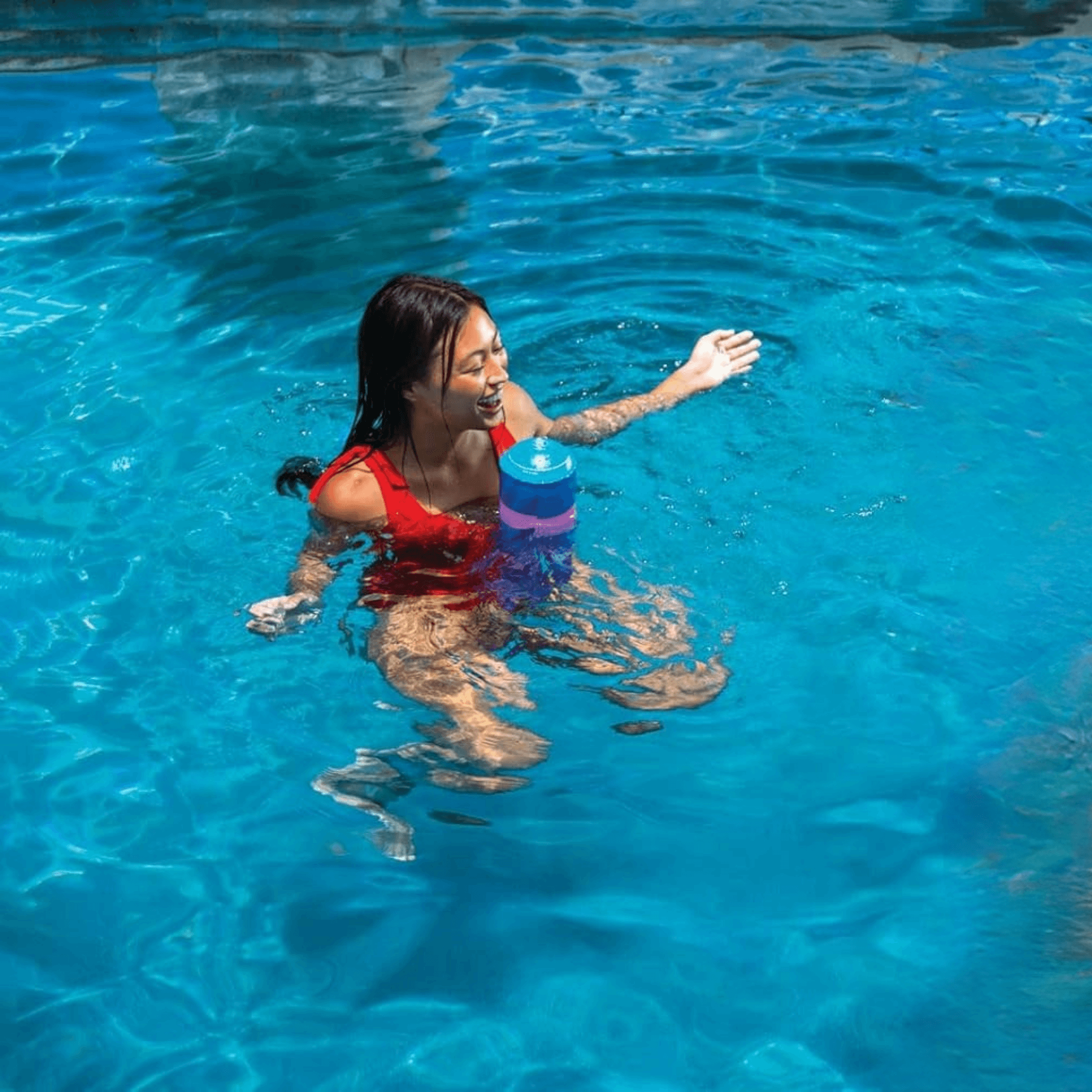 Woman in a pool holding a blue and purple toy