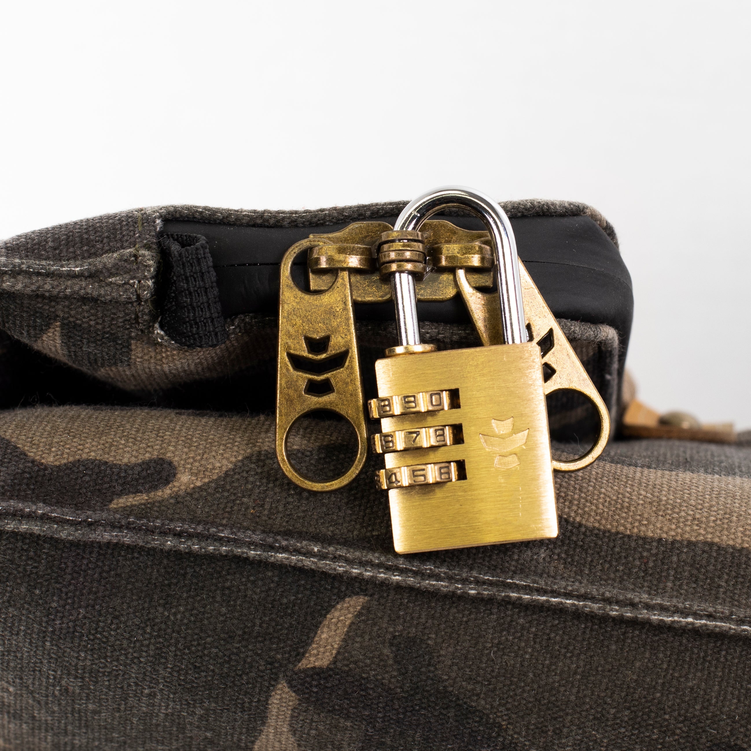 Brass padlock and keychain on a camouflage bag with a white background