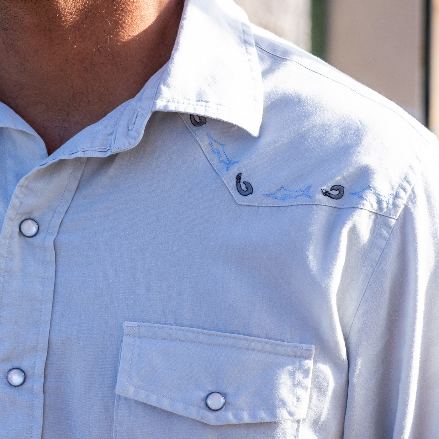 Light blue shirt with embroidered details on collar and chest pocket.