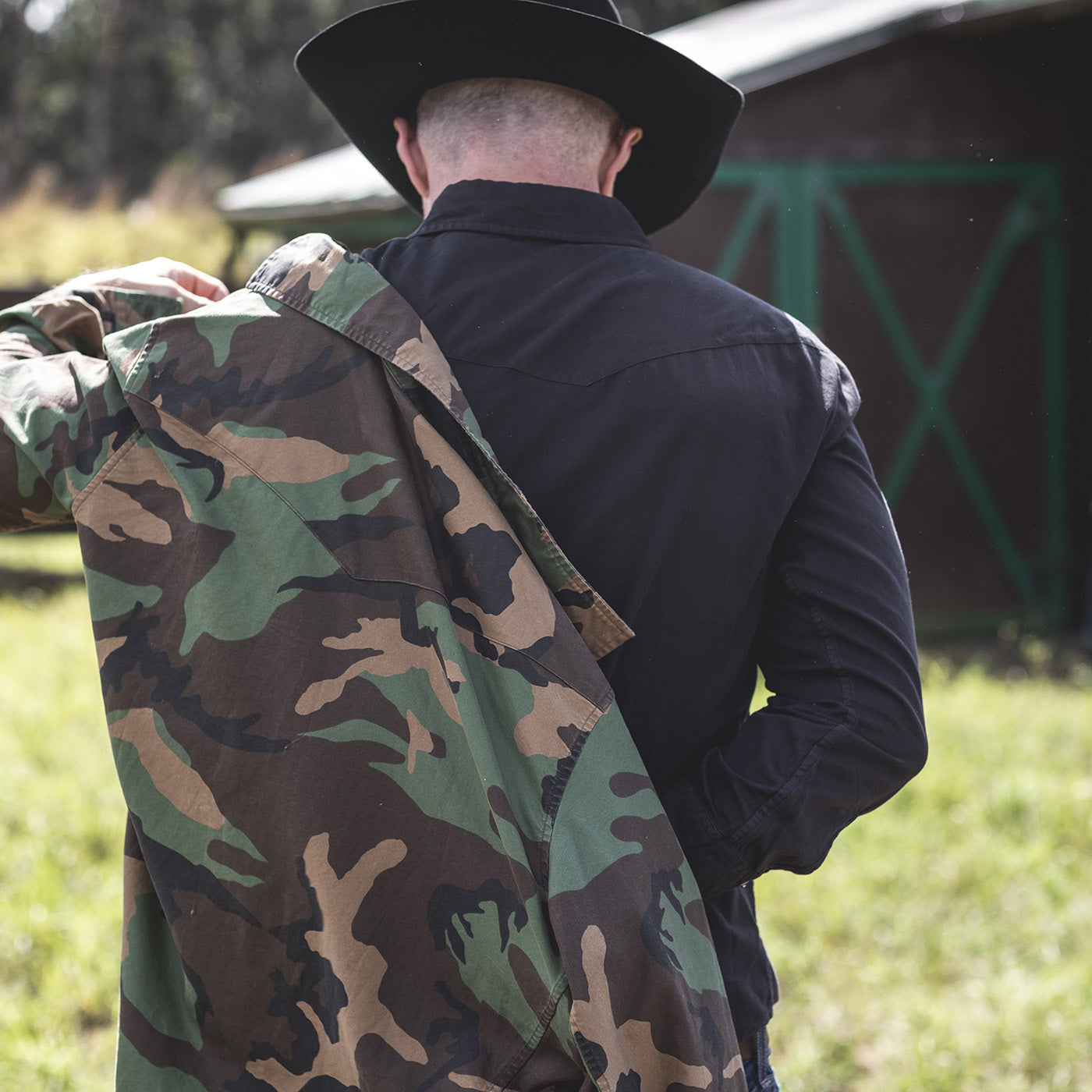 Person wearing a black jacket and camouflage jacket outdoors