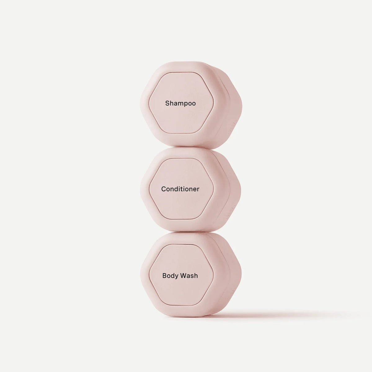 Three hexagonal green shampoo, conditioner, and body wash containers stacked vertically on a clean white background.