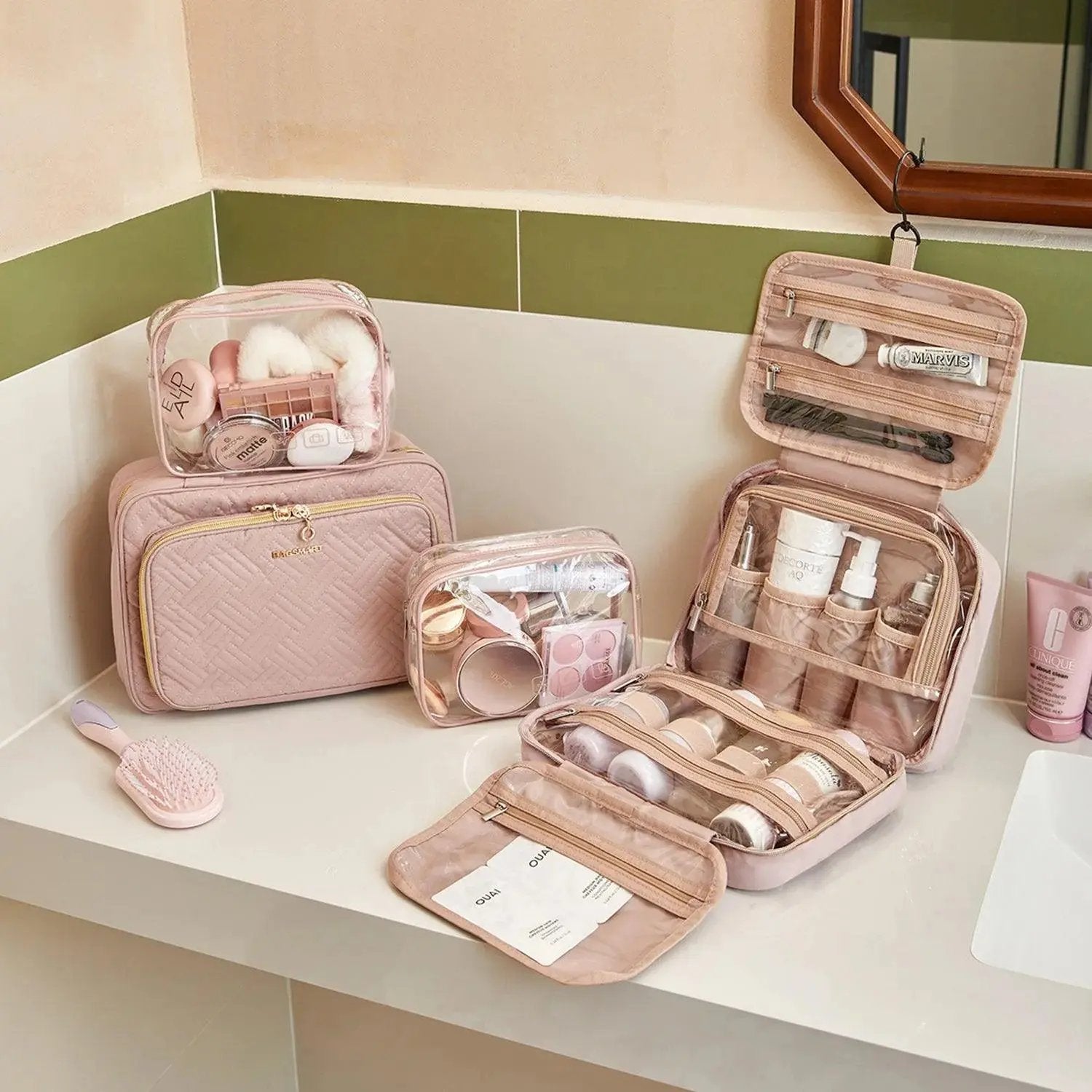 Set of pink cosmetic bags with travel accessories on a white surface.