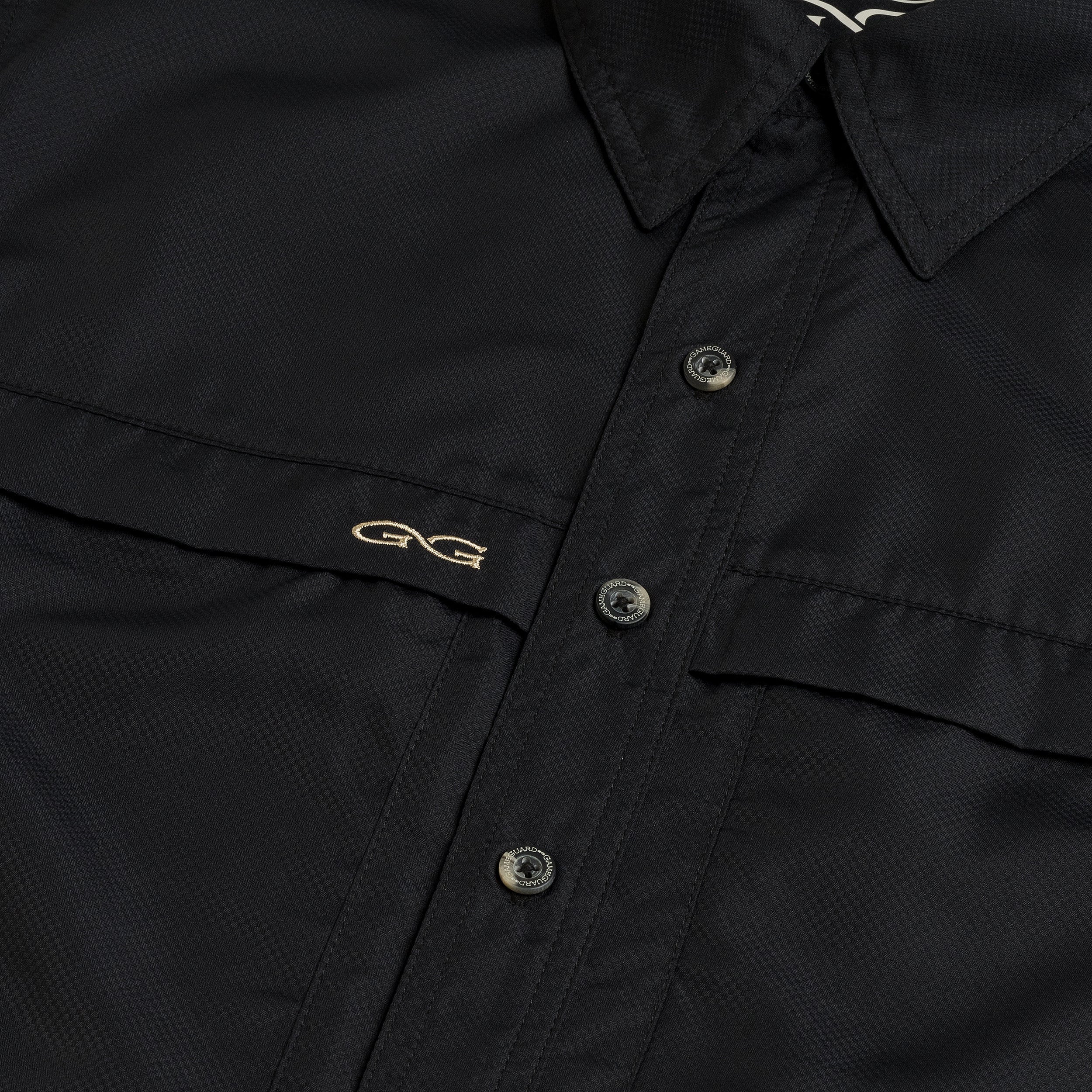 Close-up of a black jacket with buttons and a brand logo on the chest.