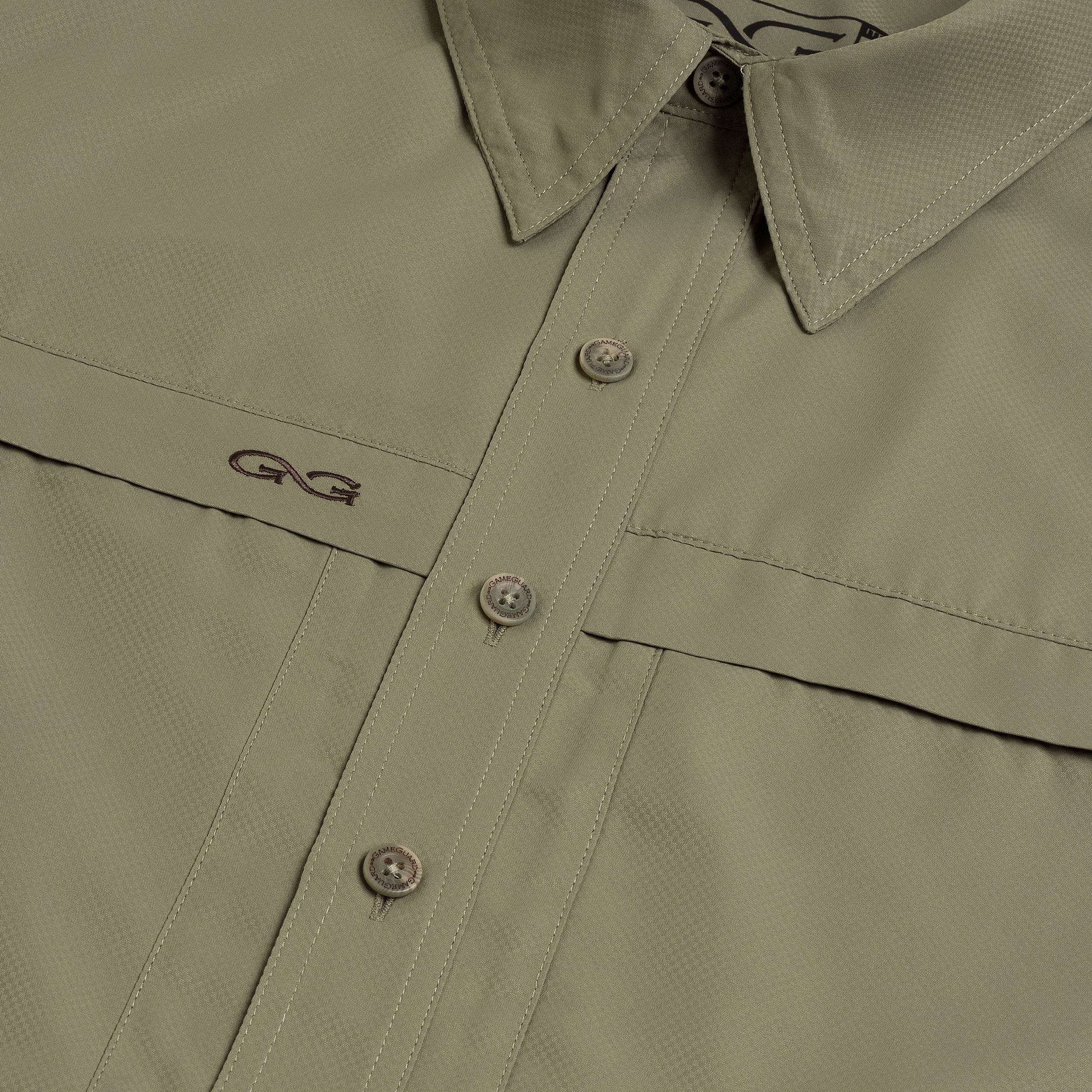 Close-up of a green shirt with buttons and a brand logo on a white background