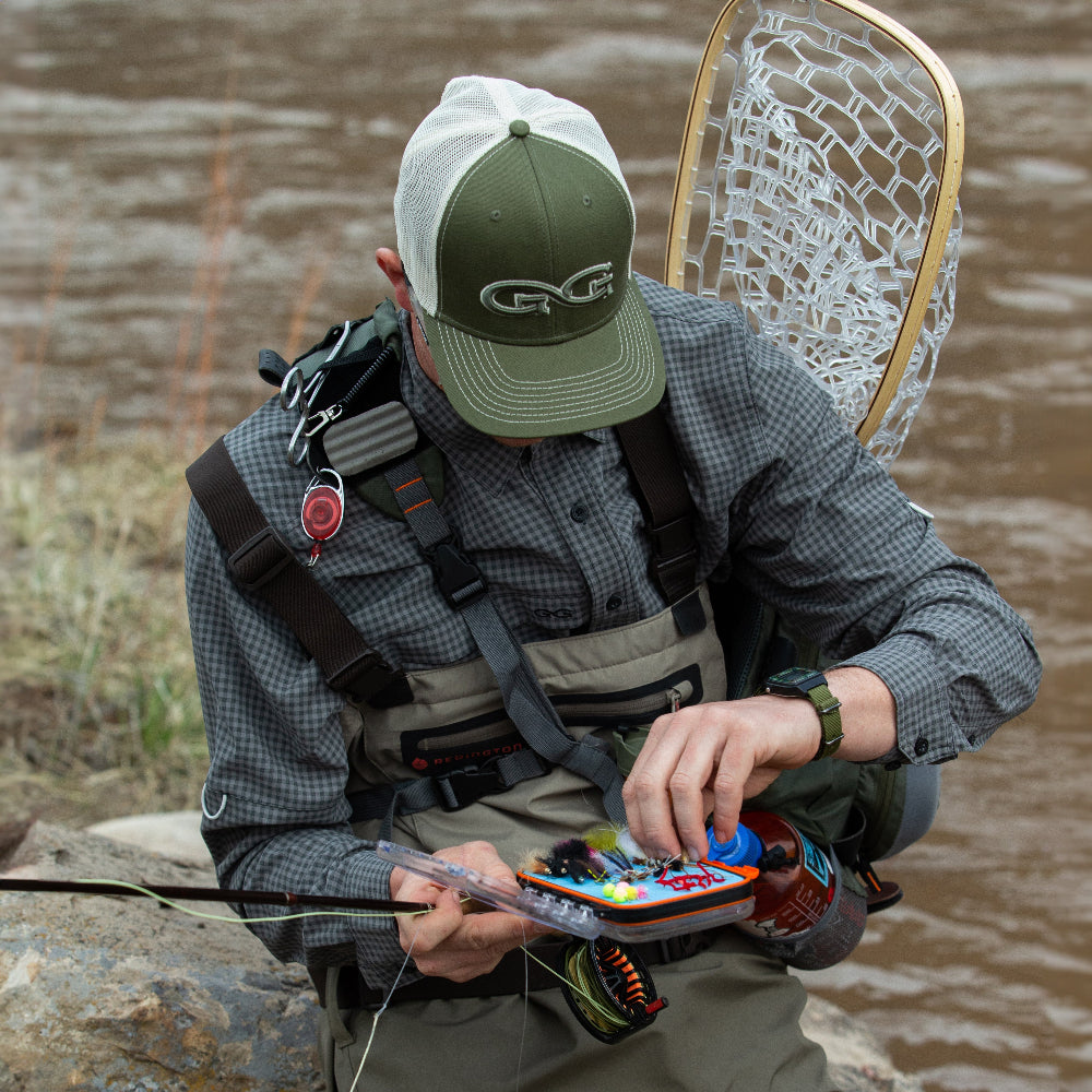Person preparing fishing gear by a body of water