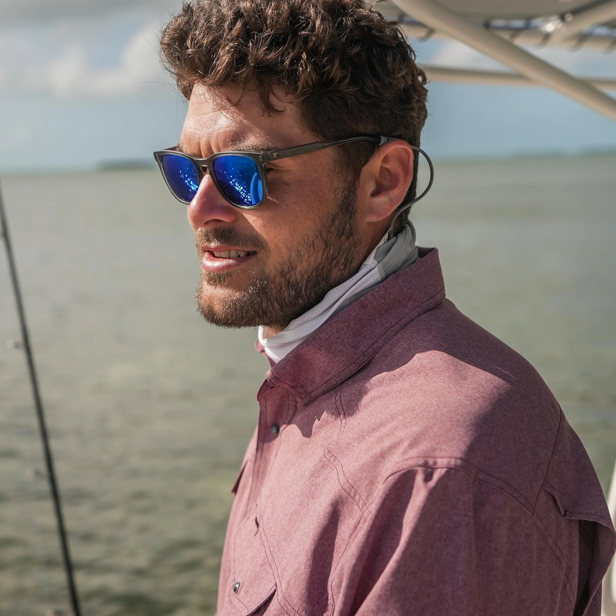 Man wearing sunglasses and a maroon shirt by water