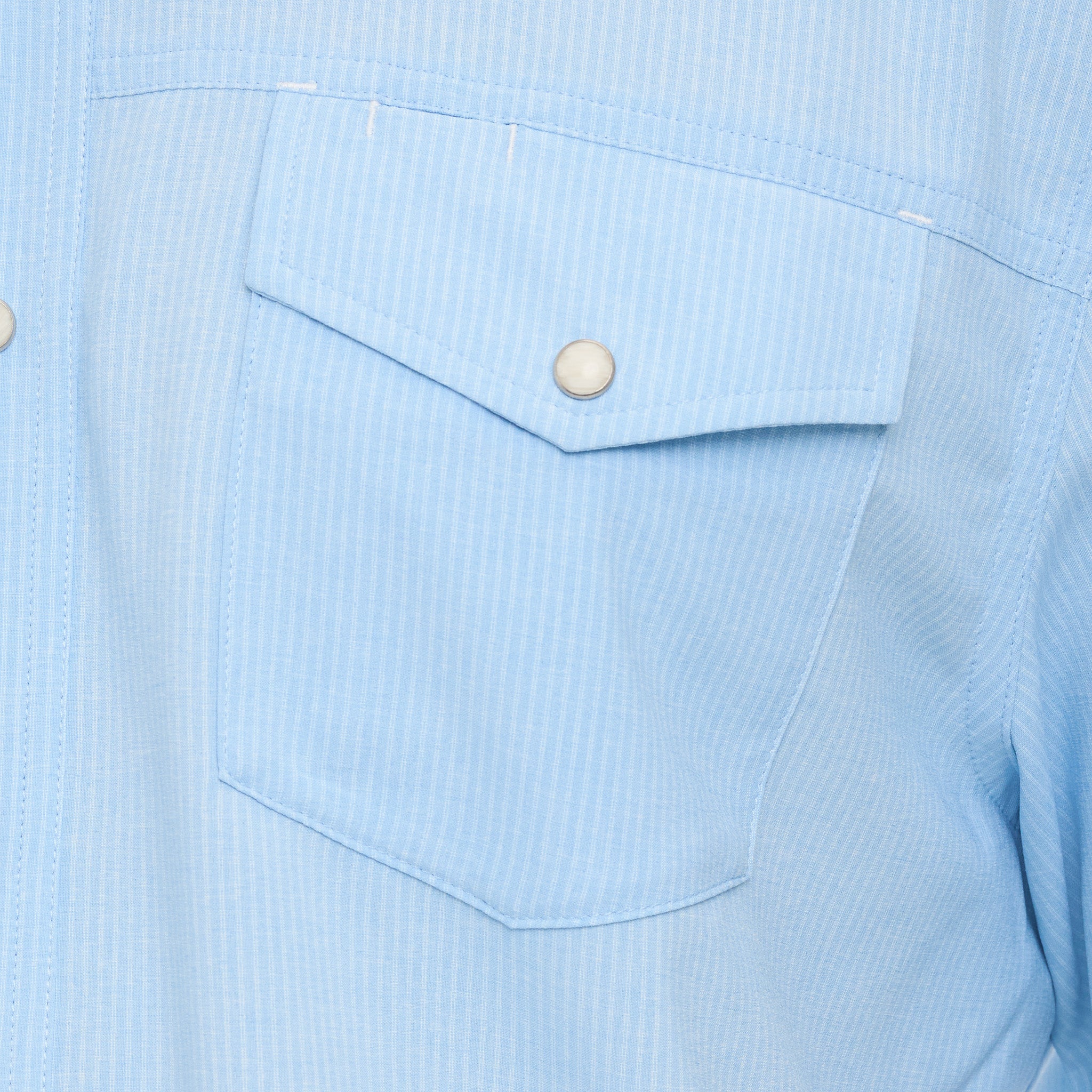 Close-up of a light blue shirt with a pocket and button