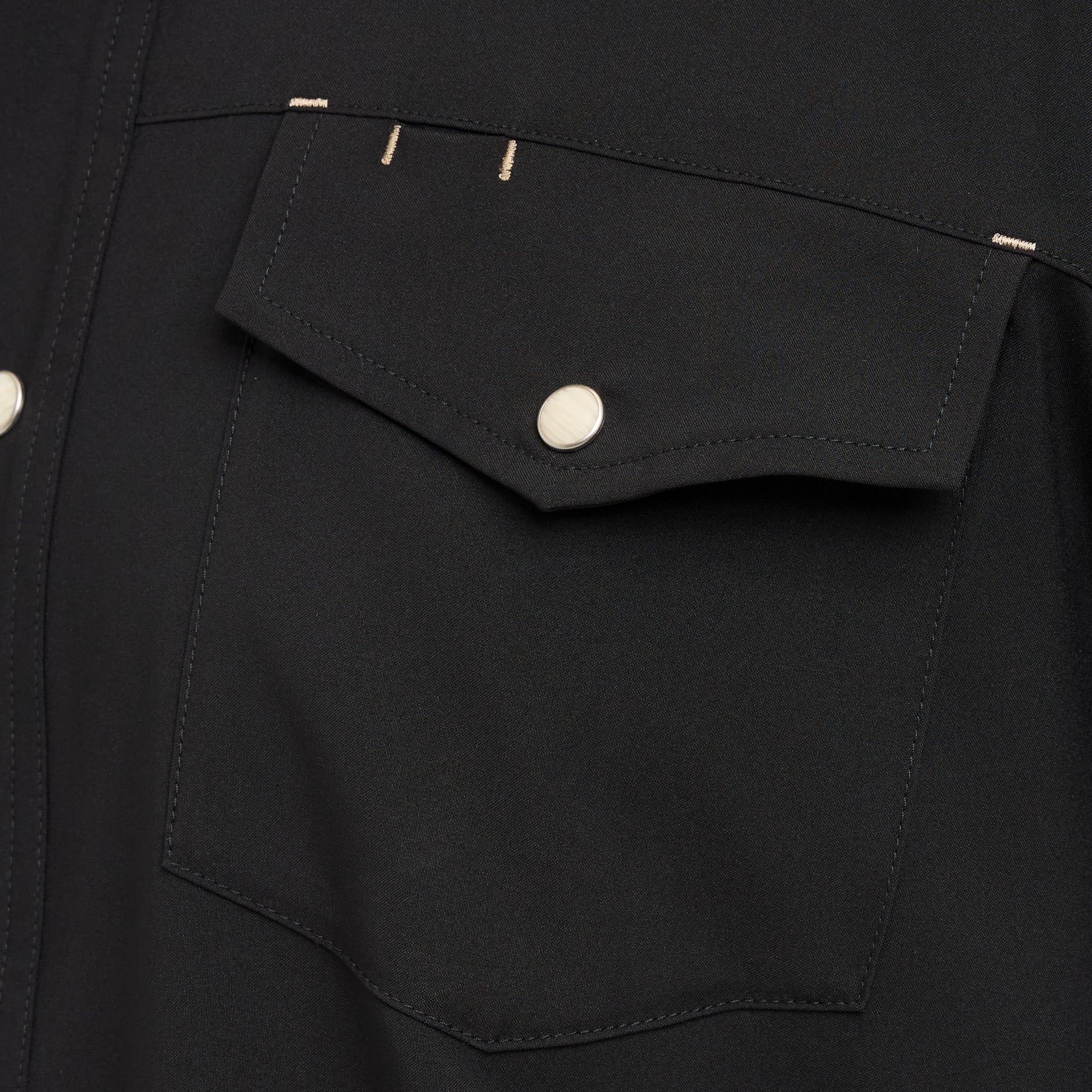 Close-up of a black jacket with a pocket and button details