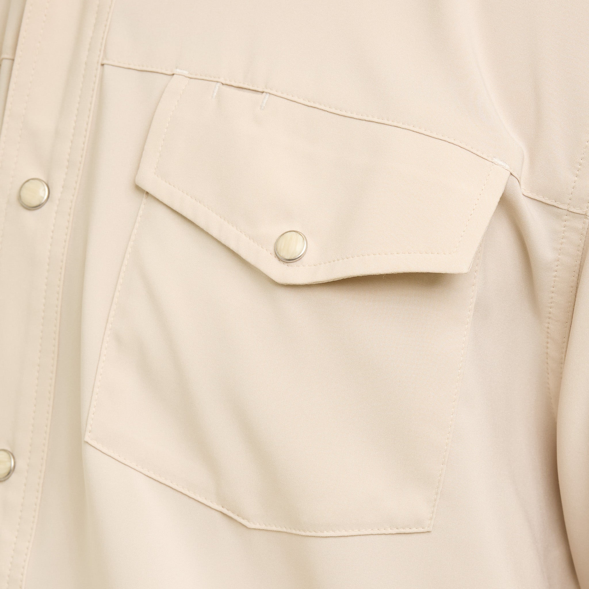 Close-up of a beige jacket with a pocket and button details