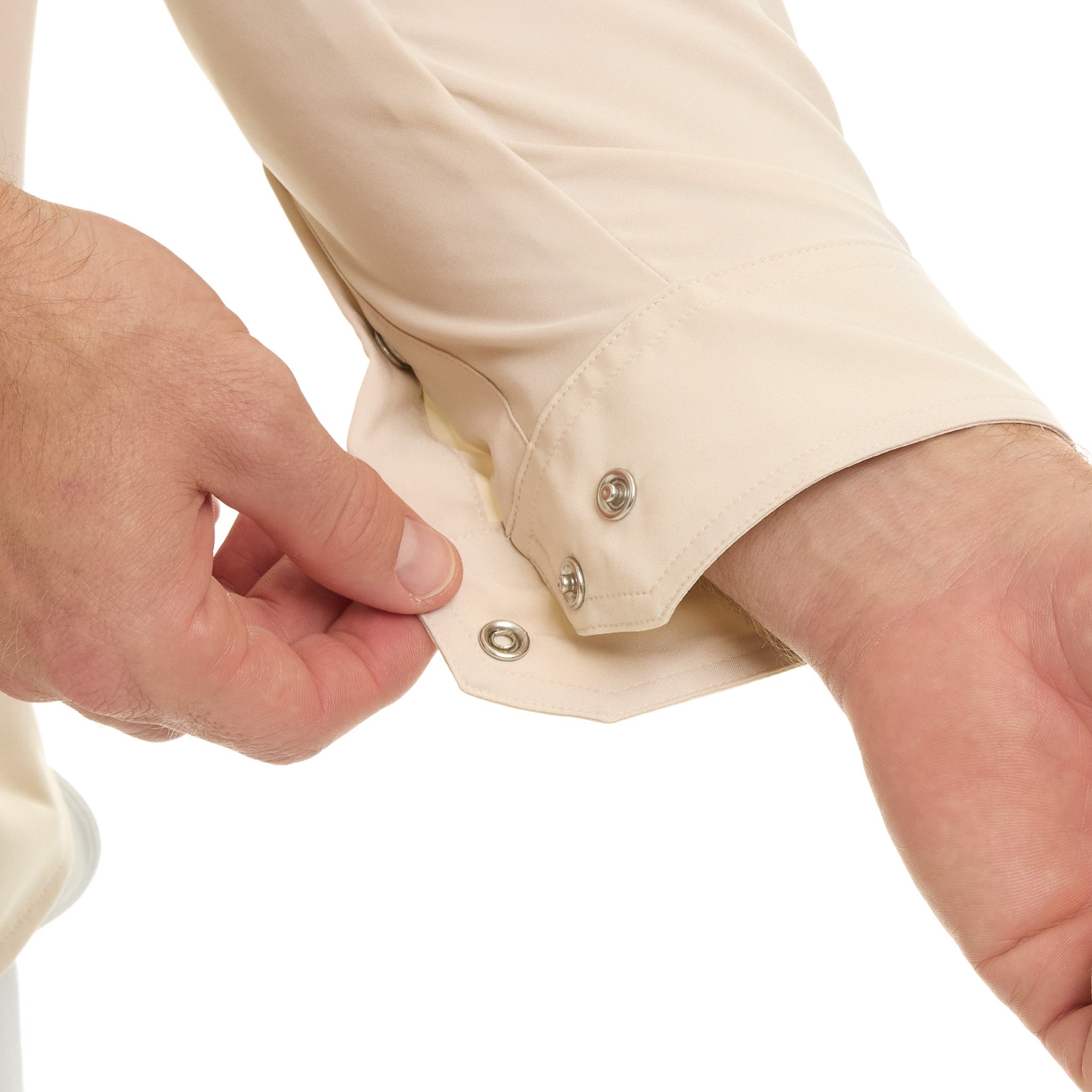 Close-up of a person buttoning a beige shirt on a white background
