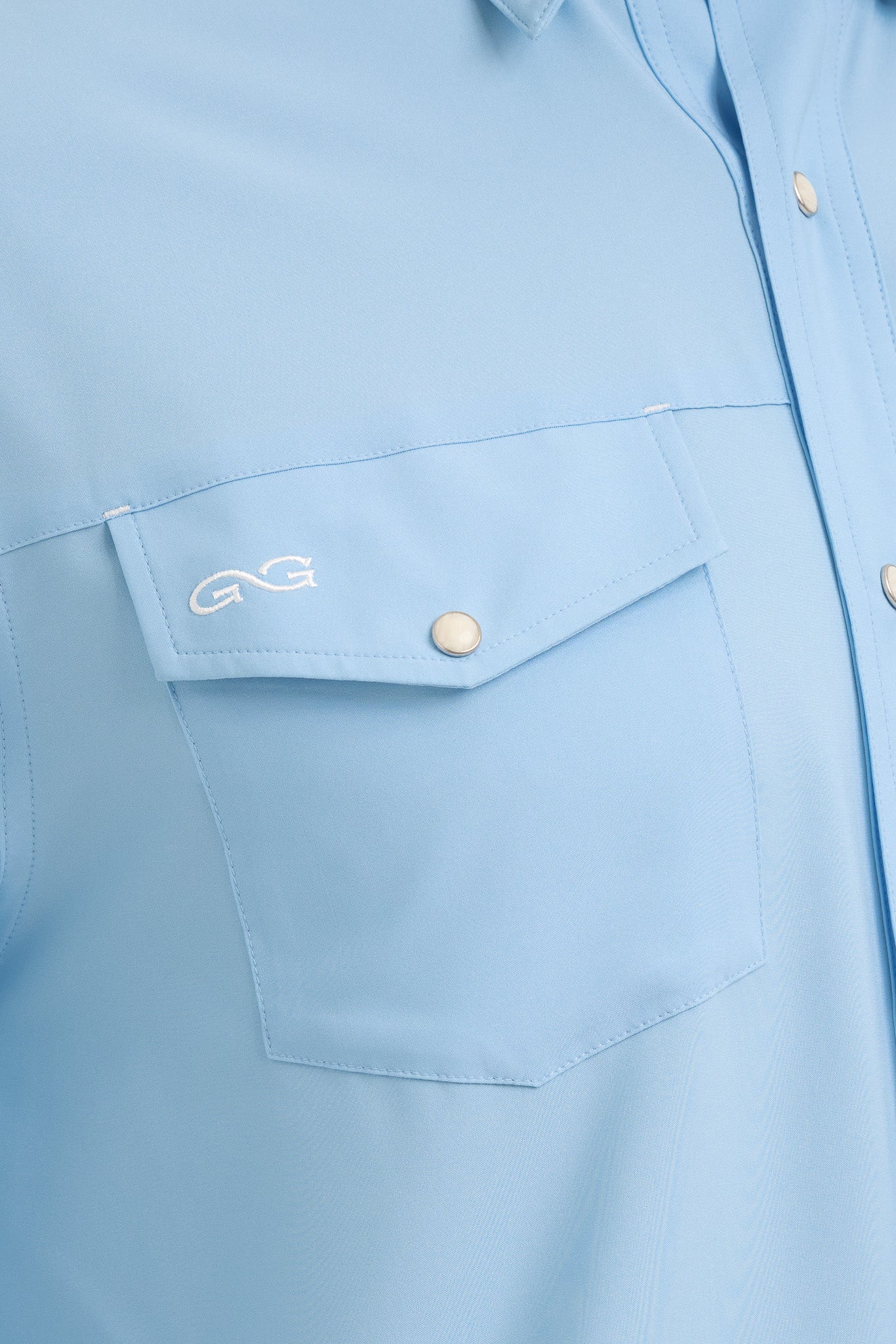 Close-up of a light blue shirt with a pocket and button details.