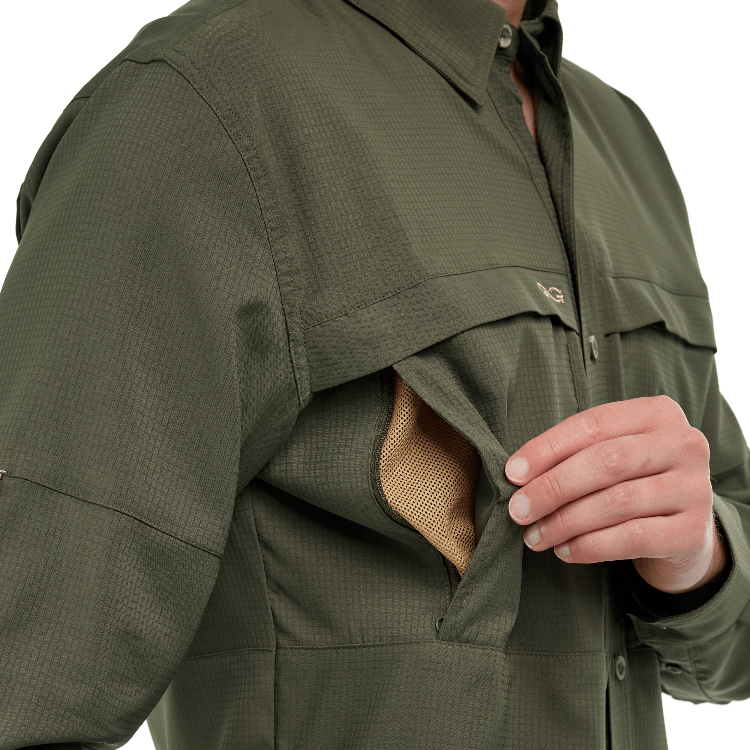 Close-up of a person wearing a green jacket with a pocket open, revealing beige fabric.