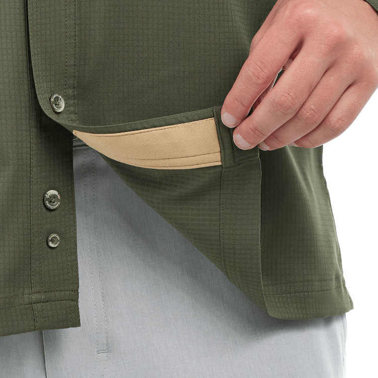Close-up of a person wearing a green jacket with a pocket, showing a beige lining.