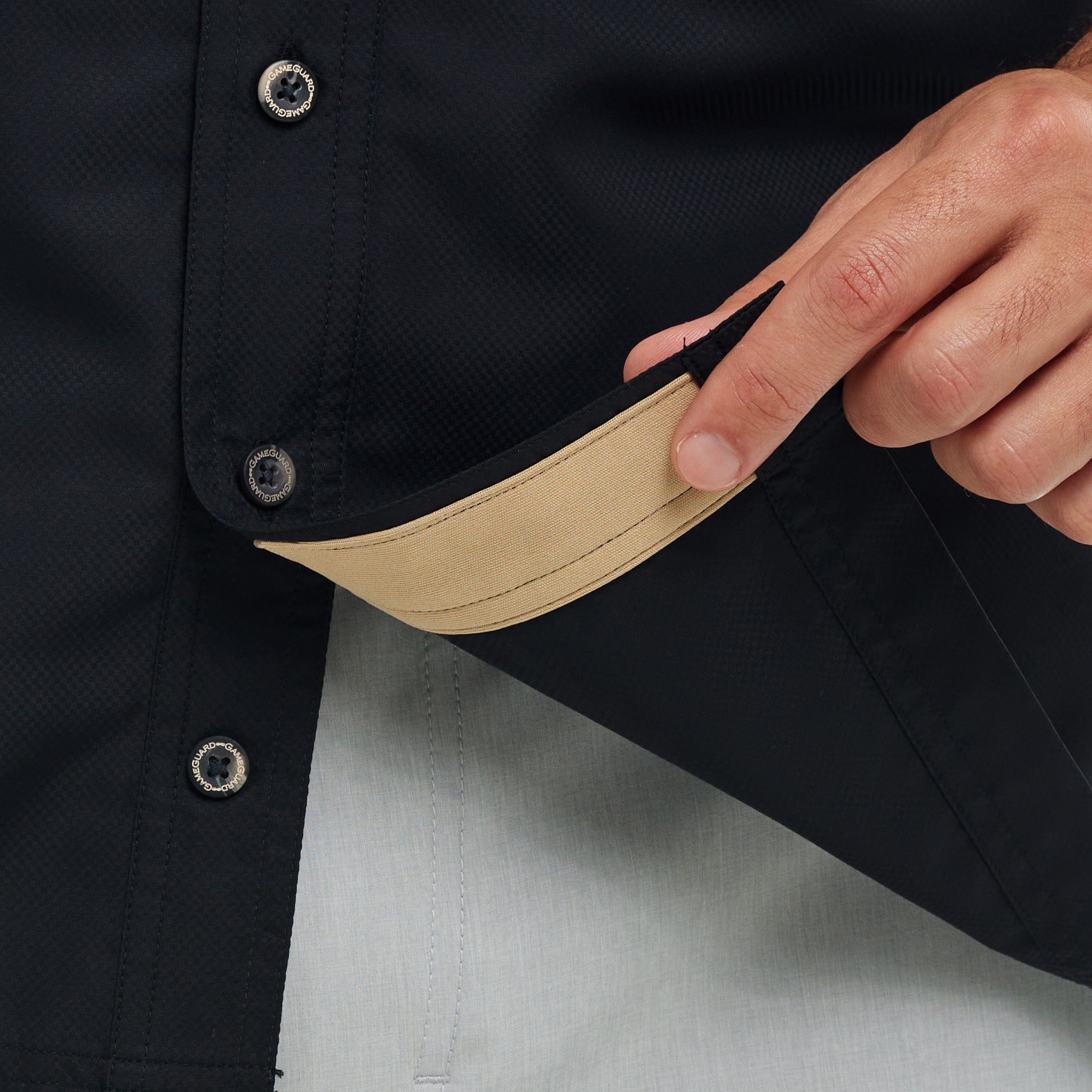 Close-up of a black jacket with beige lining and a hand adjusting it.