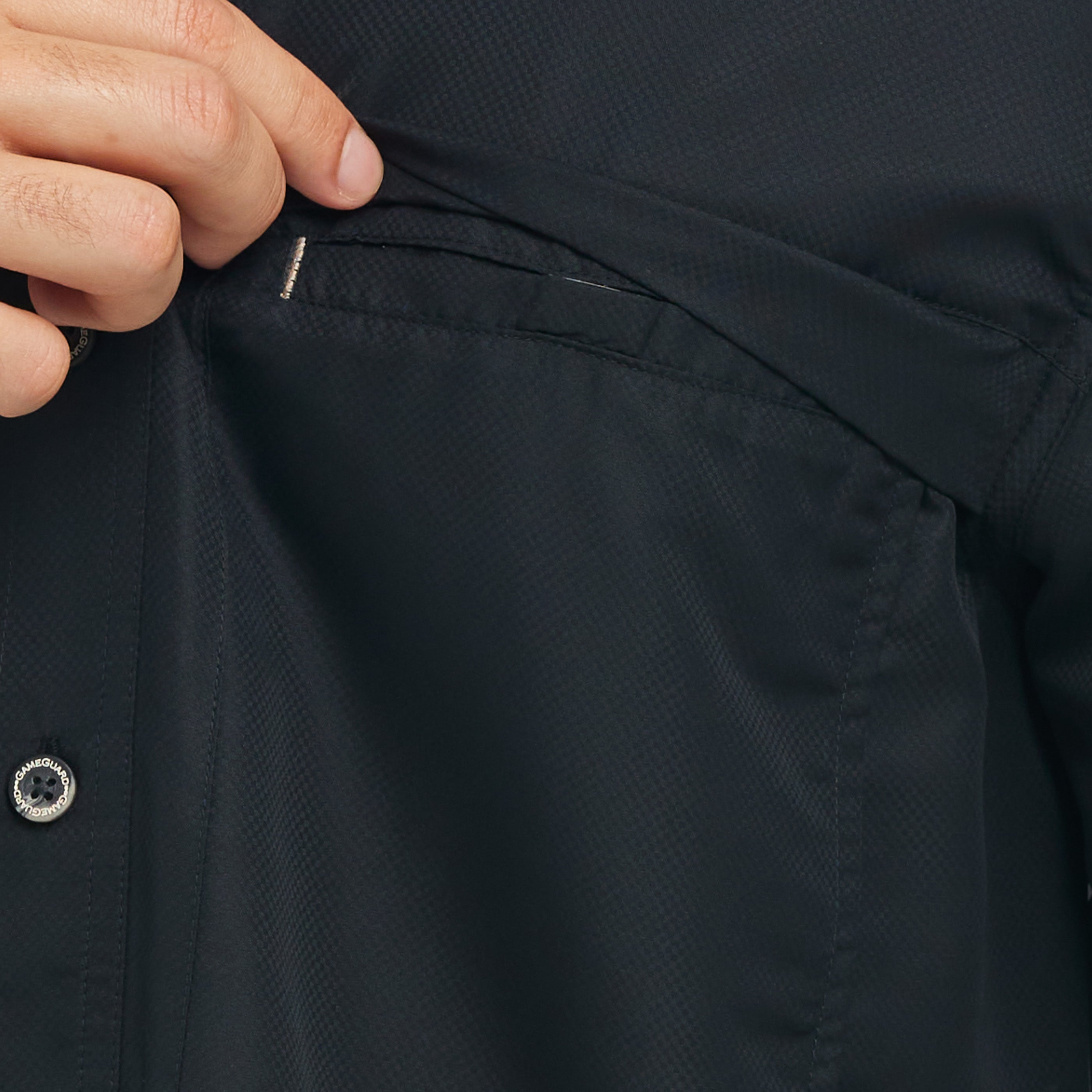 Close-up of a person buttoning a black shirt with a button visible.