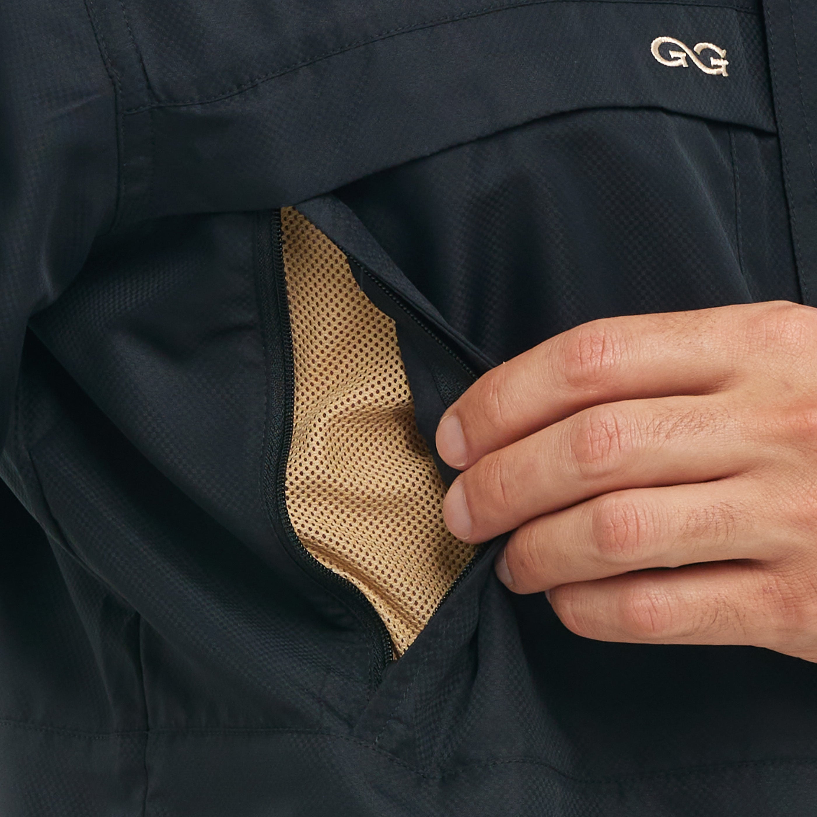 Close-up of a hand adjusting the collar of a dark jacket with a brand logo.