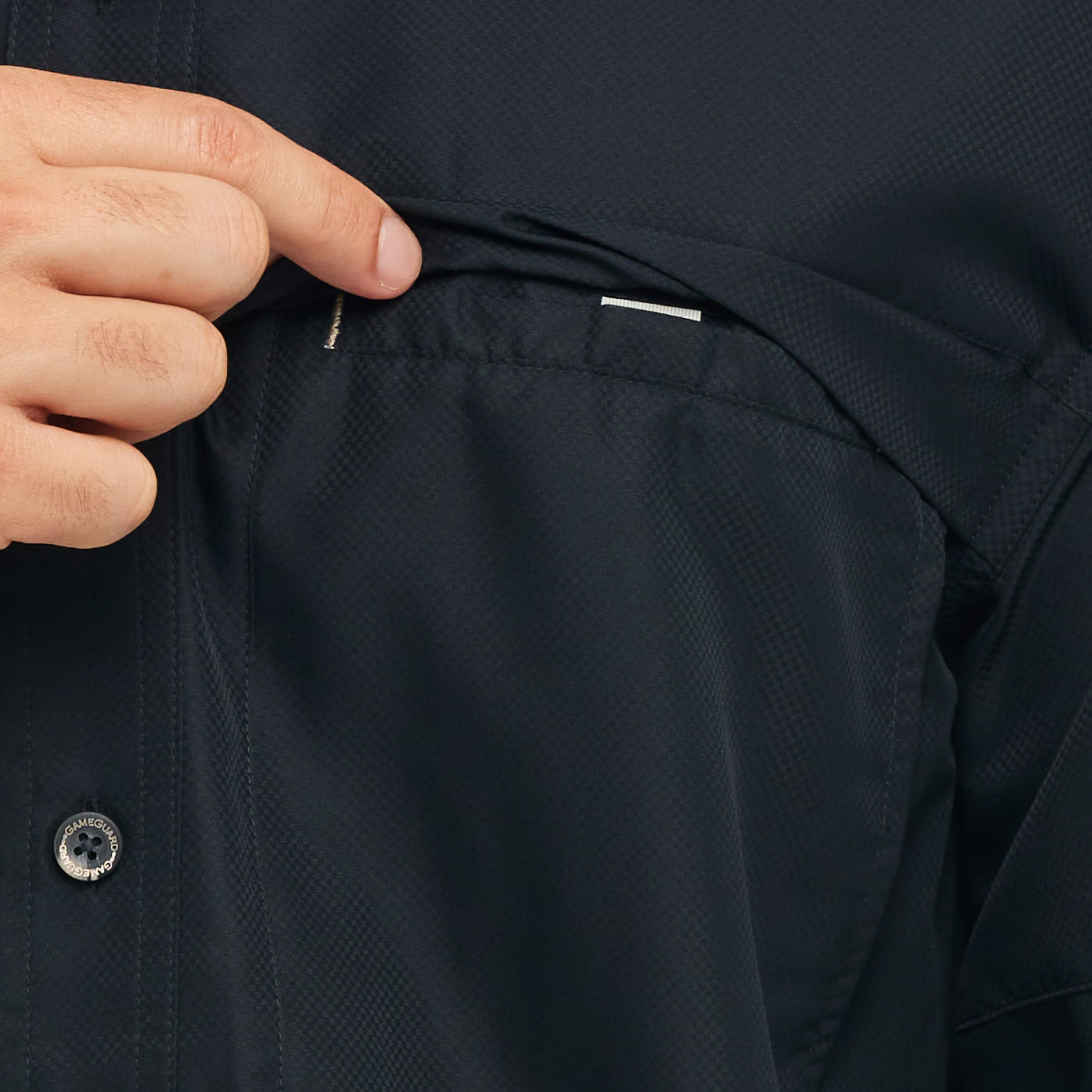 Close-up of a person adjusting the waistband of a dark jacket with a button visible.