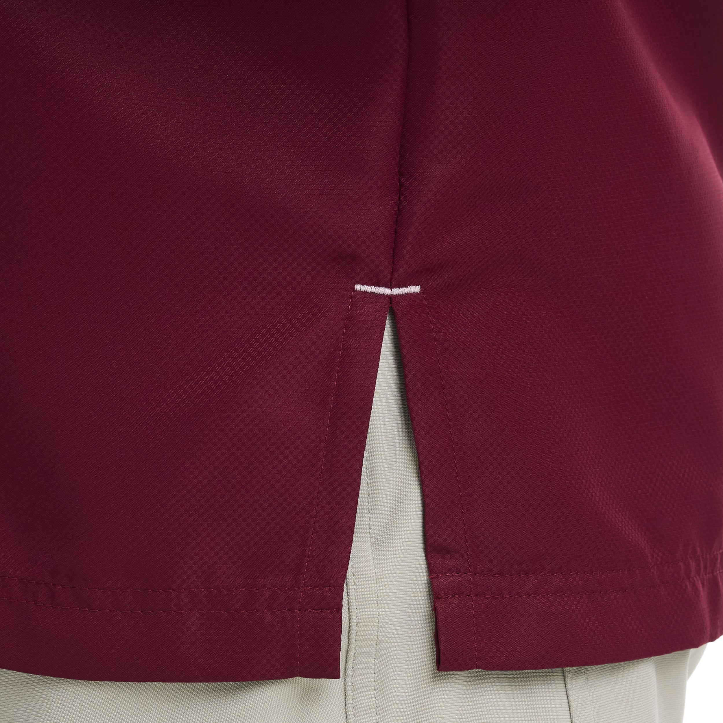 Close-up of a maroon shirt with beige pants, focusing on the hemline.