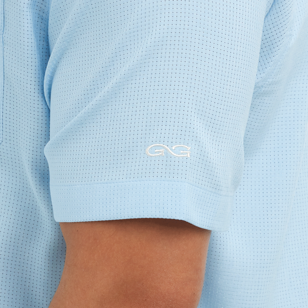 Light blue polo shirt with a logo on the sleeve, worn by a person.