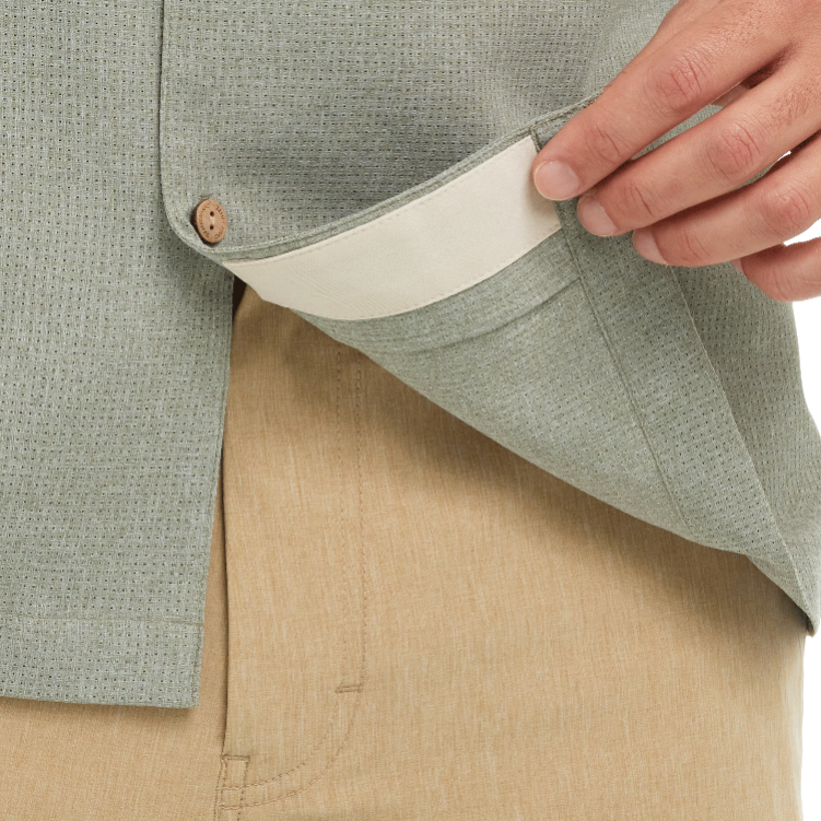 Close-up of a person wearing a light green textured jacket with beige pants.