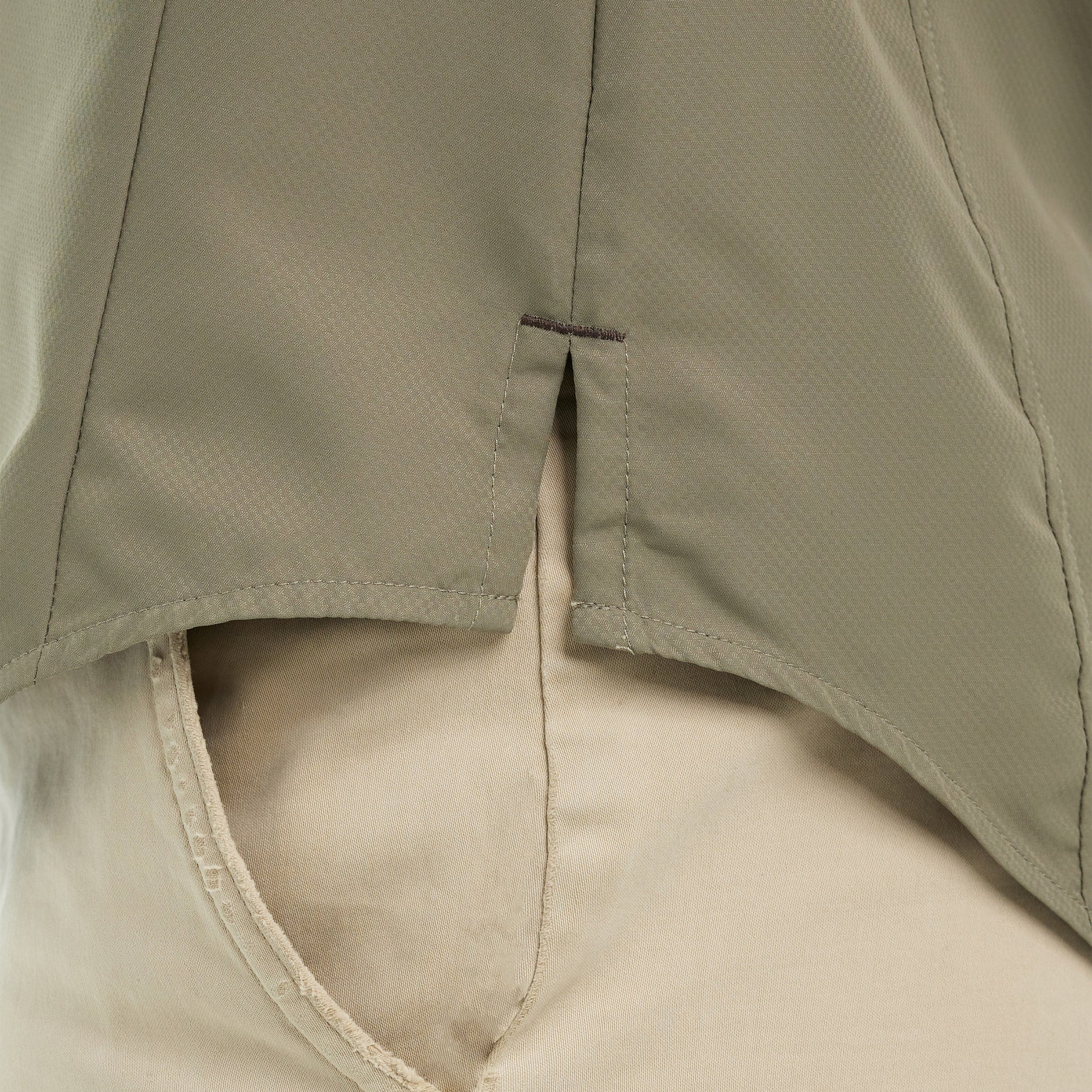 Close-up of beige pants with a green jacket over them
