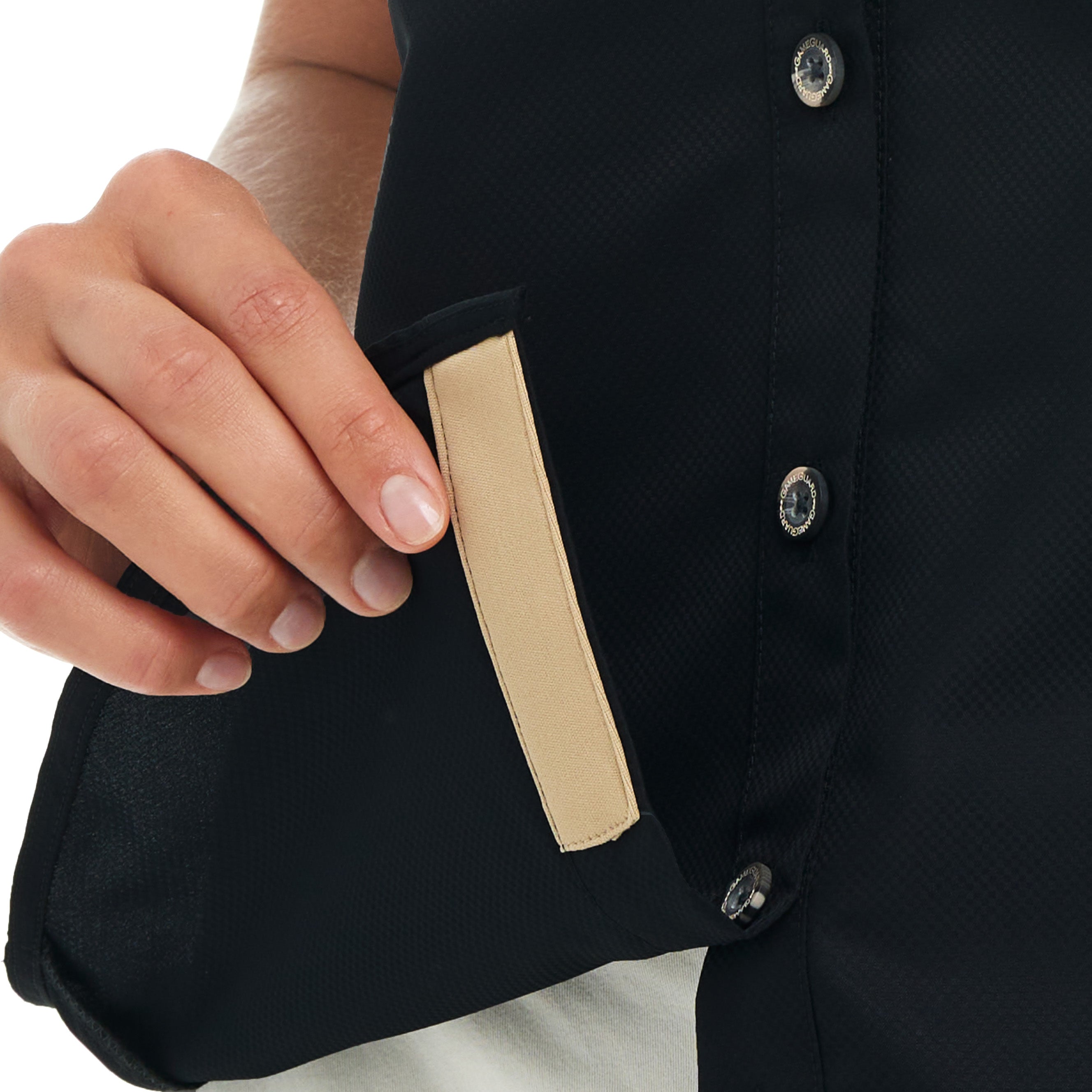 Close-up of a hand holding a black clutch with a beige strap.
