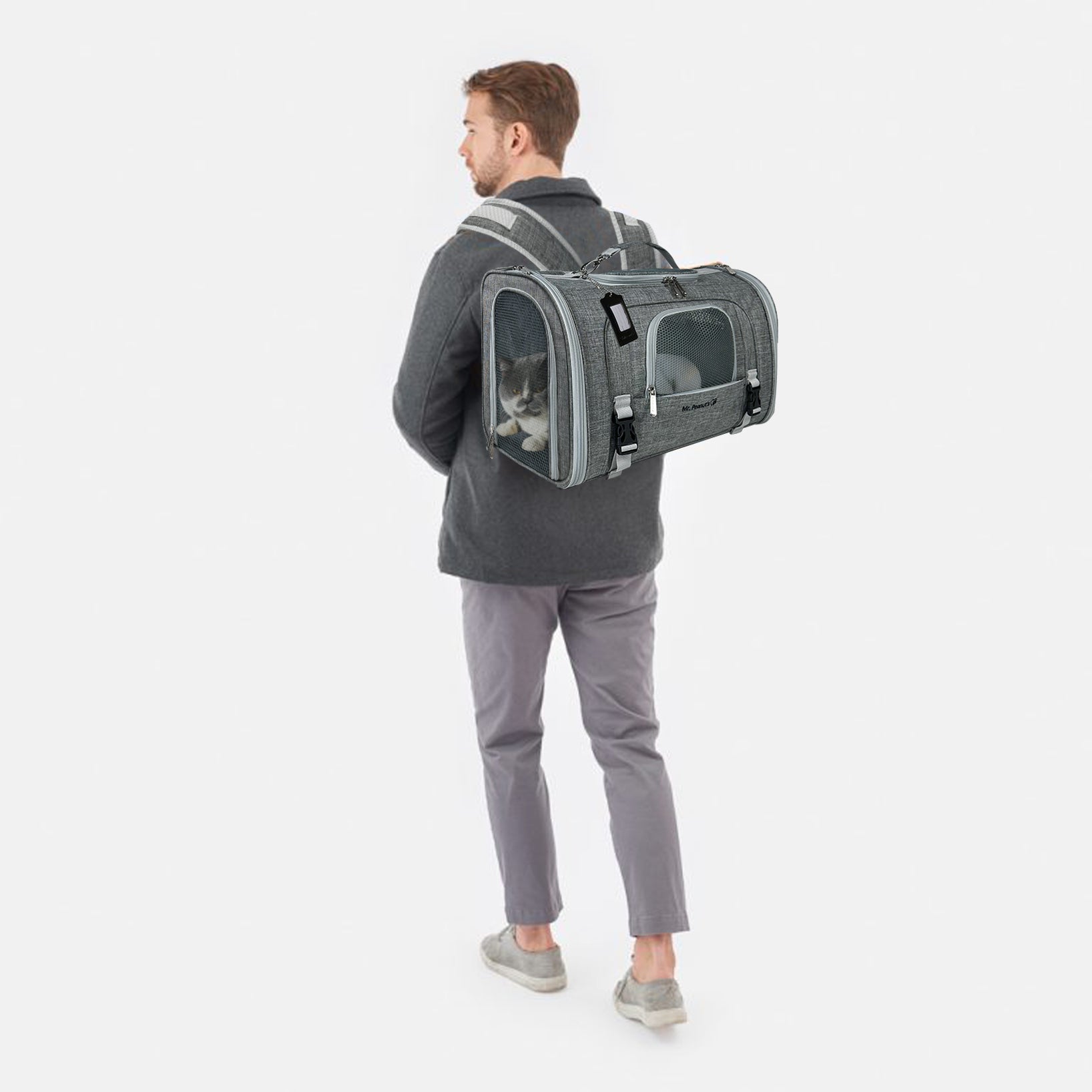Person wearing a gray pet carrier backpack with a cat inside on a white background
