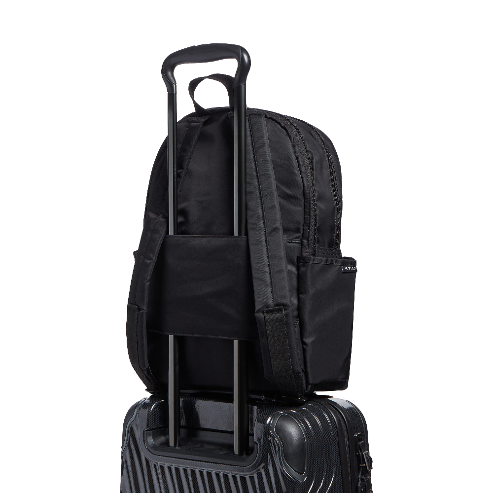 Black backpack with rolling handle on top of a suitcase