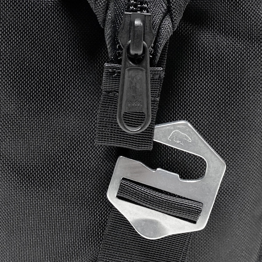 Close-up of a black backpack with a metal buckle and zipper pull.