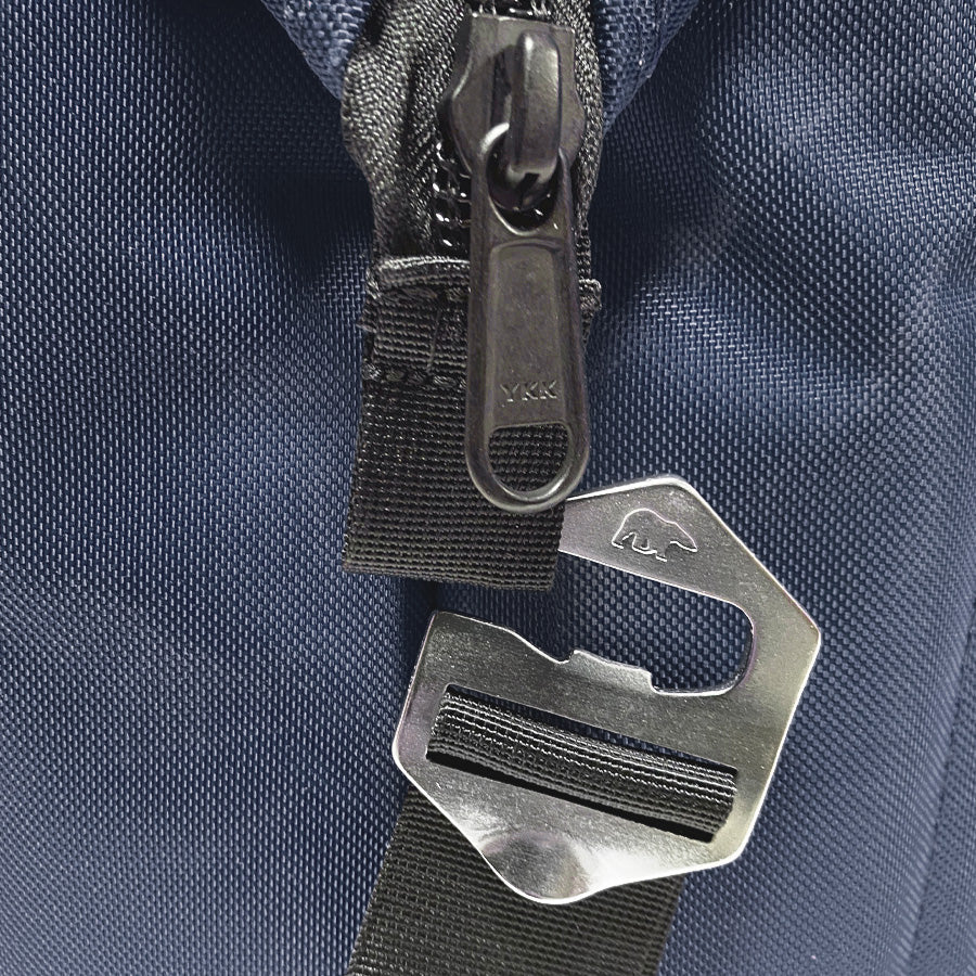 Close-up of a zipper pull and metal hook on a blue fabric background