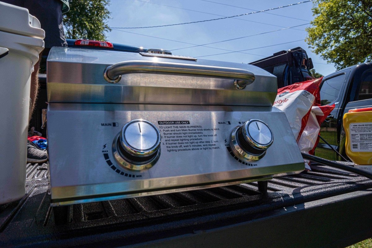 Stainless steel grill on a truck bed with trees and clear sky in the background