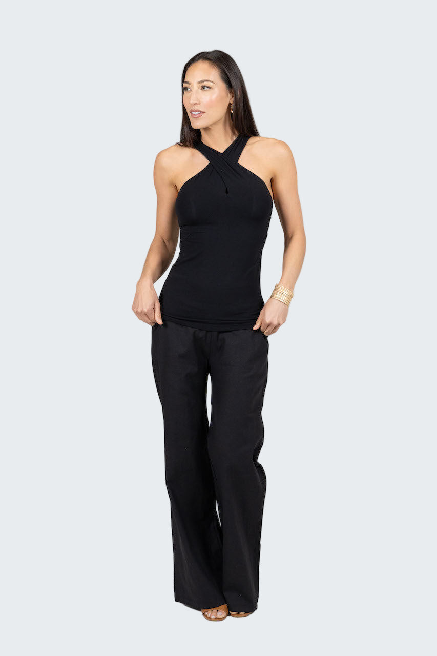 Woman wearing a black sleeveless top and black pants on a gray background