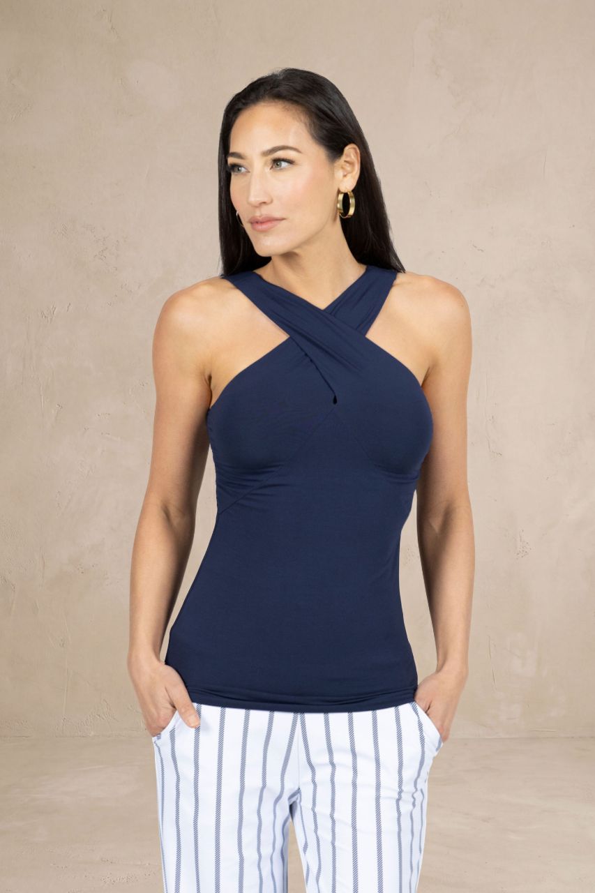 Woman wearing a navy blue halter top with white striped pants against a beige background