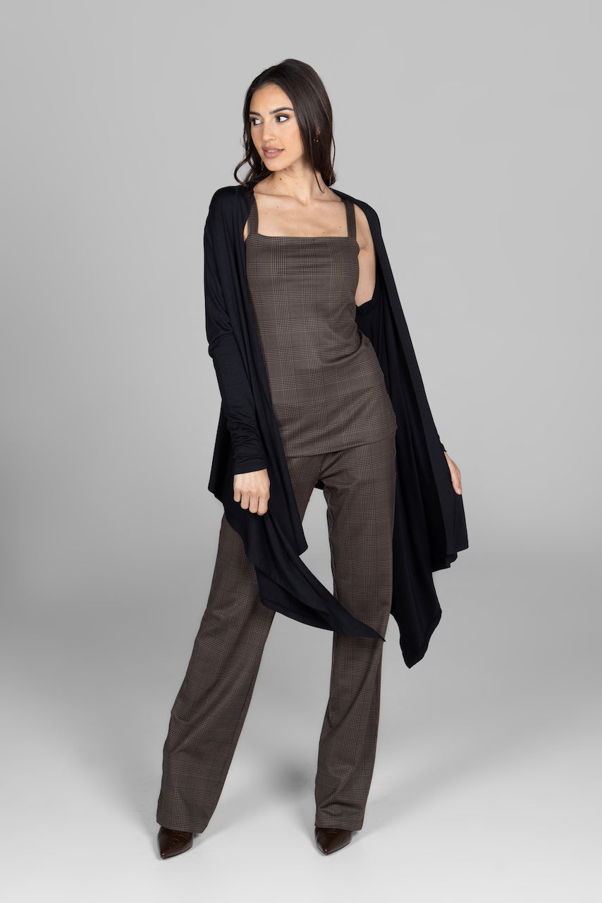 Woman wearing a brown outfit with a black cardigan on a gray background