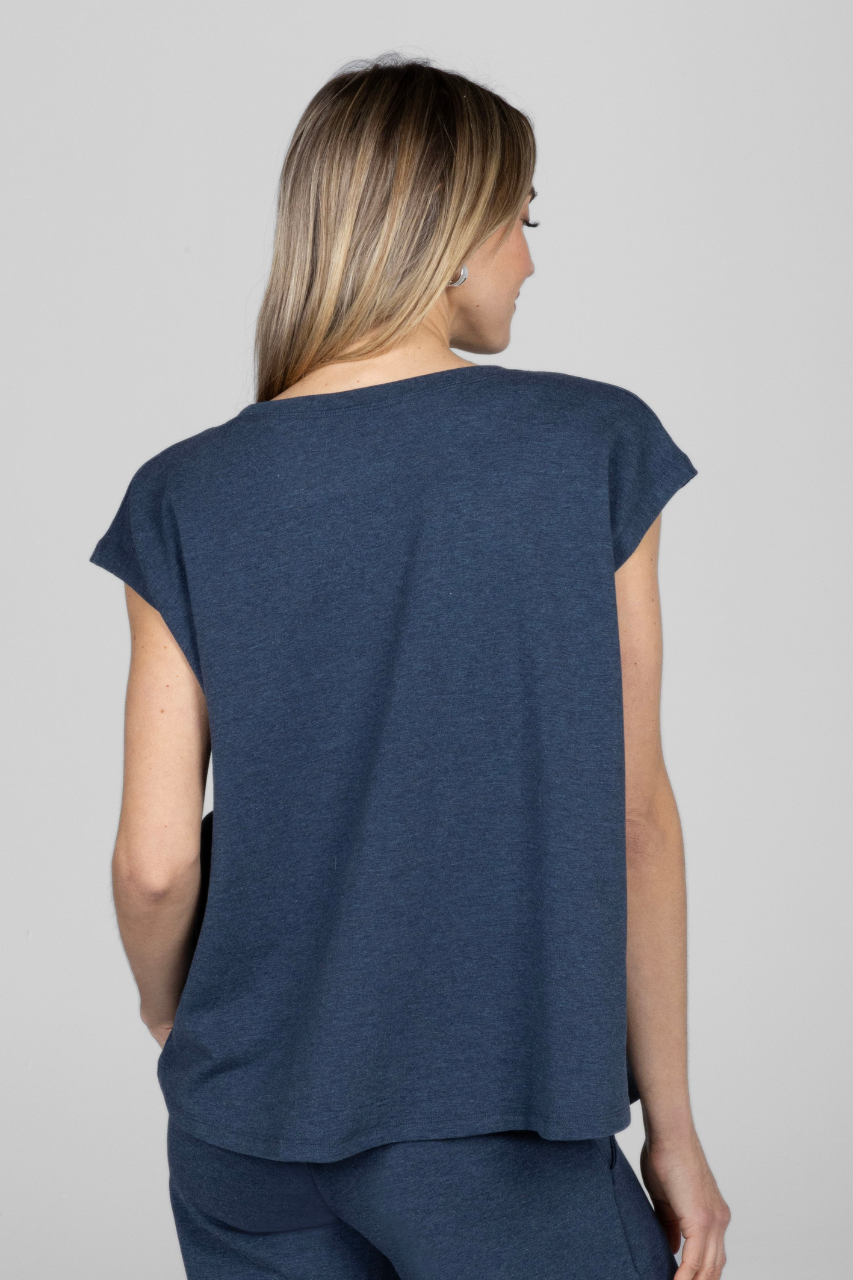 Woman wearing a blue sleeveless top against a gray background