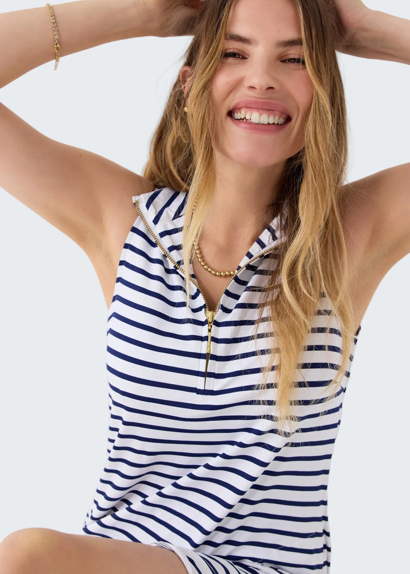 Woman wearing a blue and white striped sleeveless top on a white background