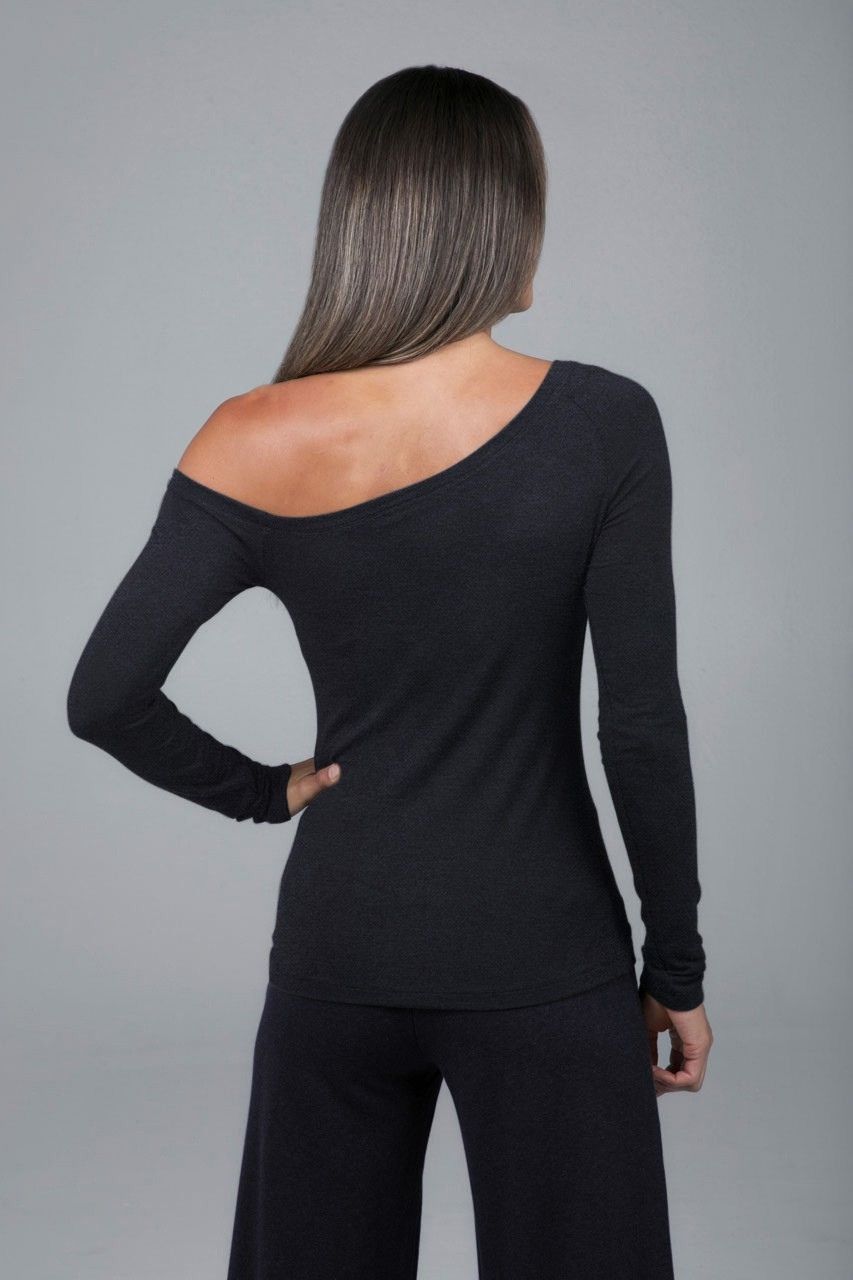 Woman wearing a black long-sleeve top and pants against a gray background