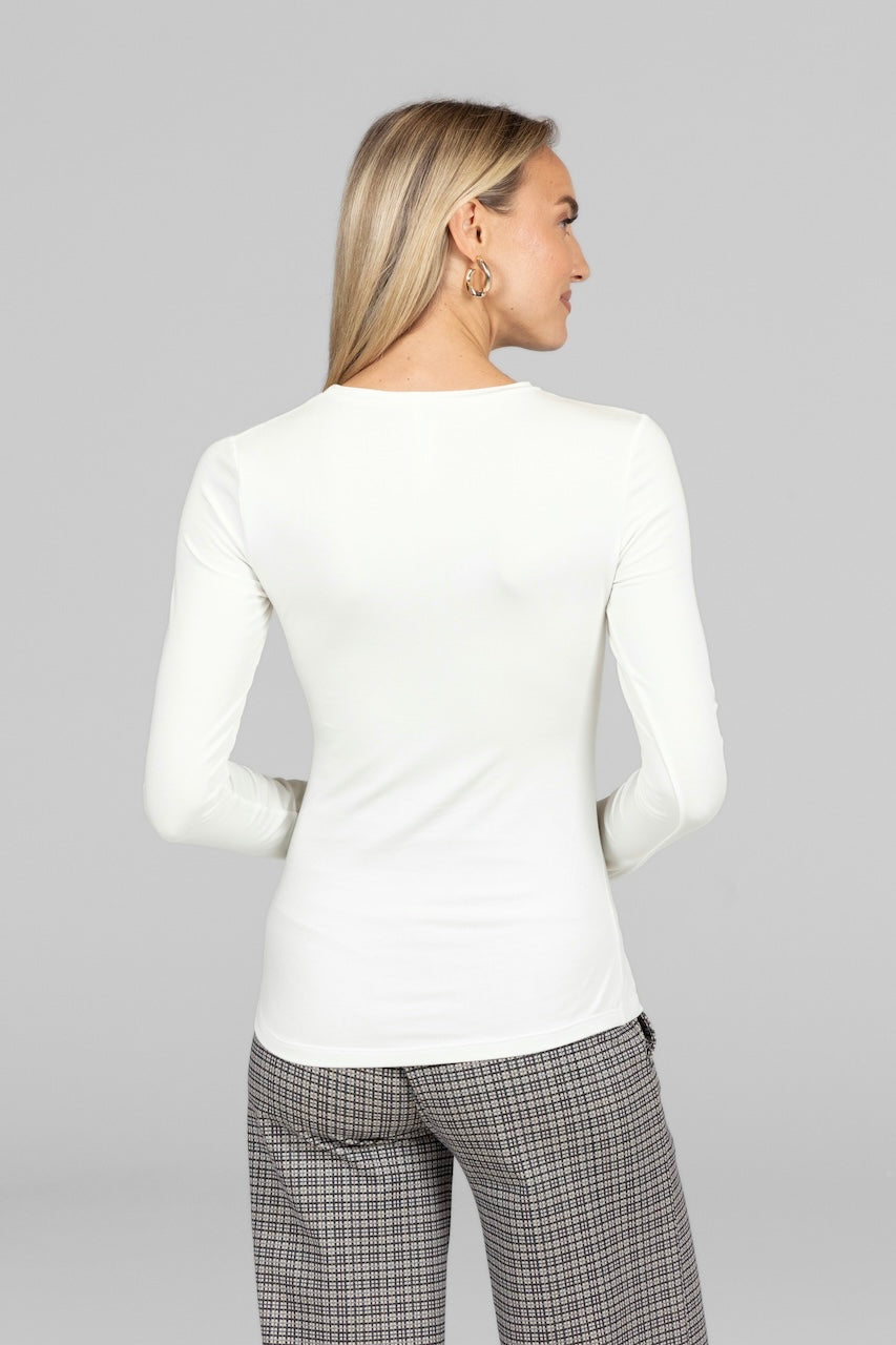 Woman wearing a white long-sleeve top and plaid pants on a gray background