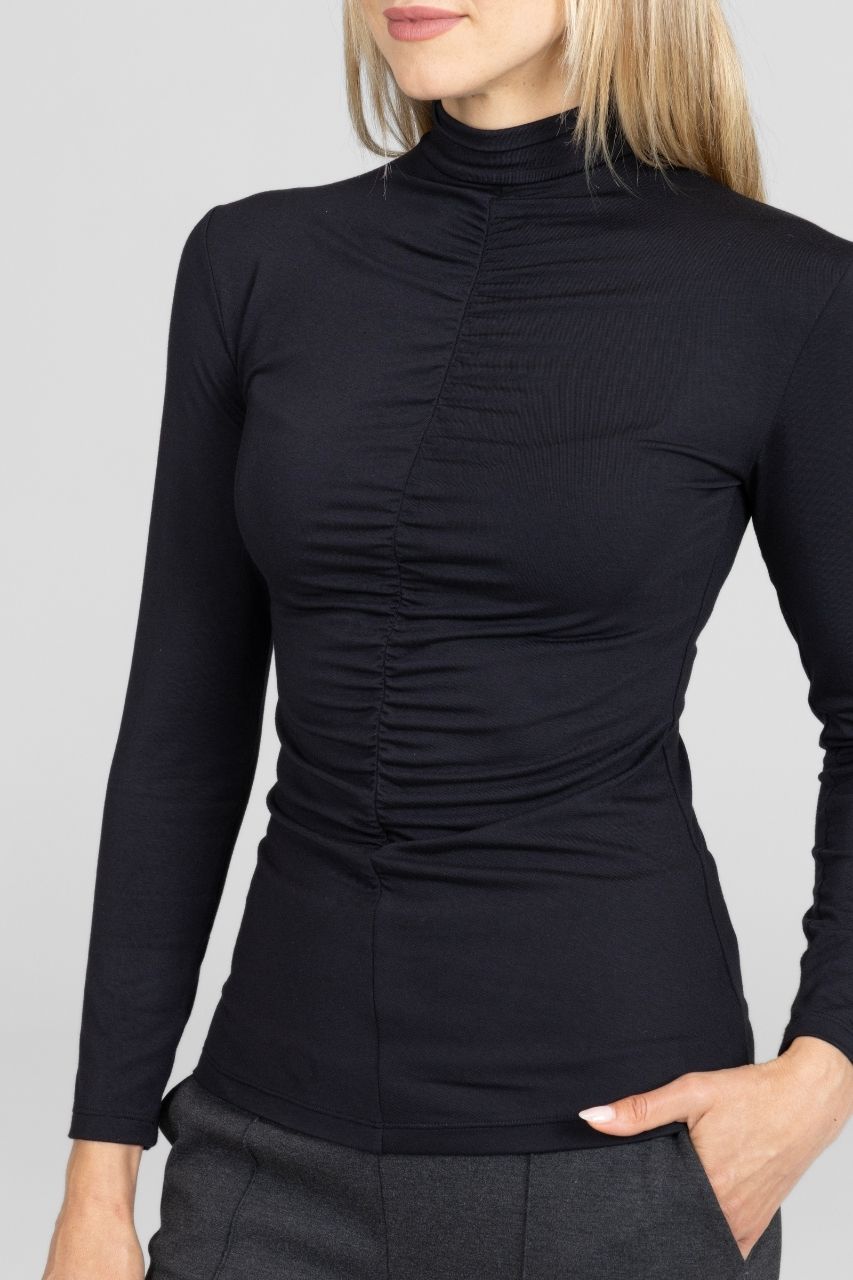 Black long-sleeve top worn by a person on a gray background