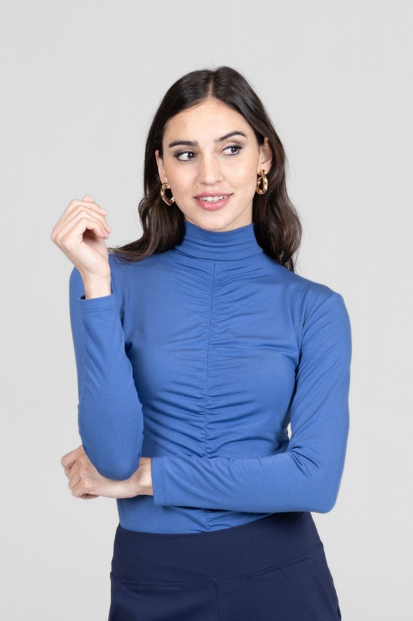 Woman wearing a blue turtleneck shirt against a plain background
