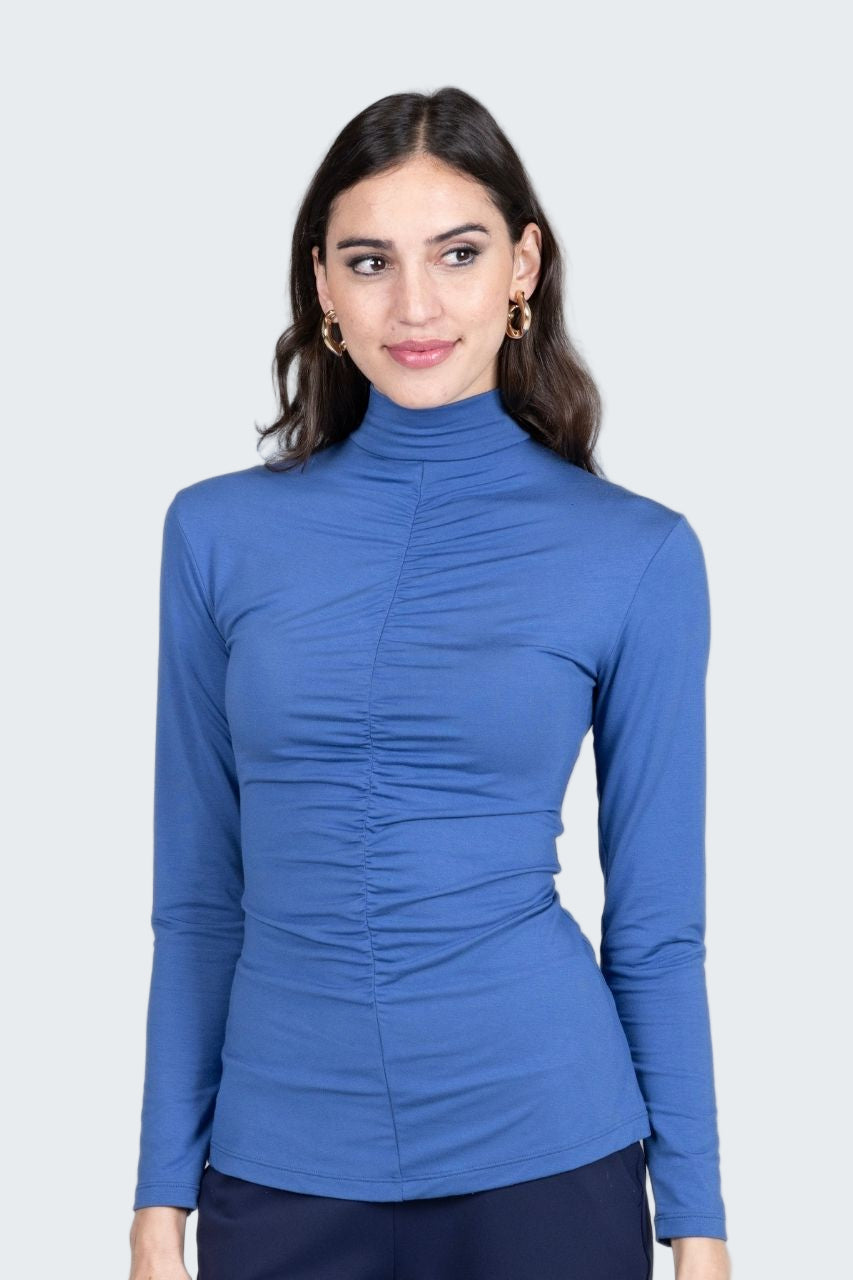Woman wearing a blue long-sleeve top against a gray background