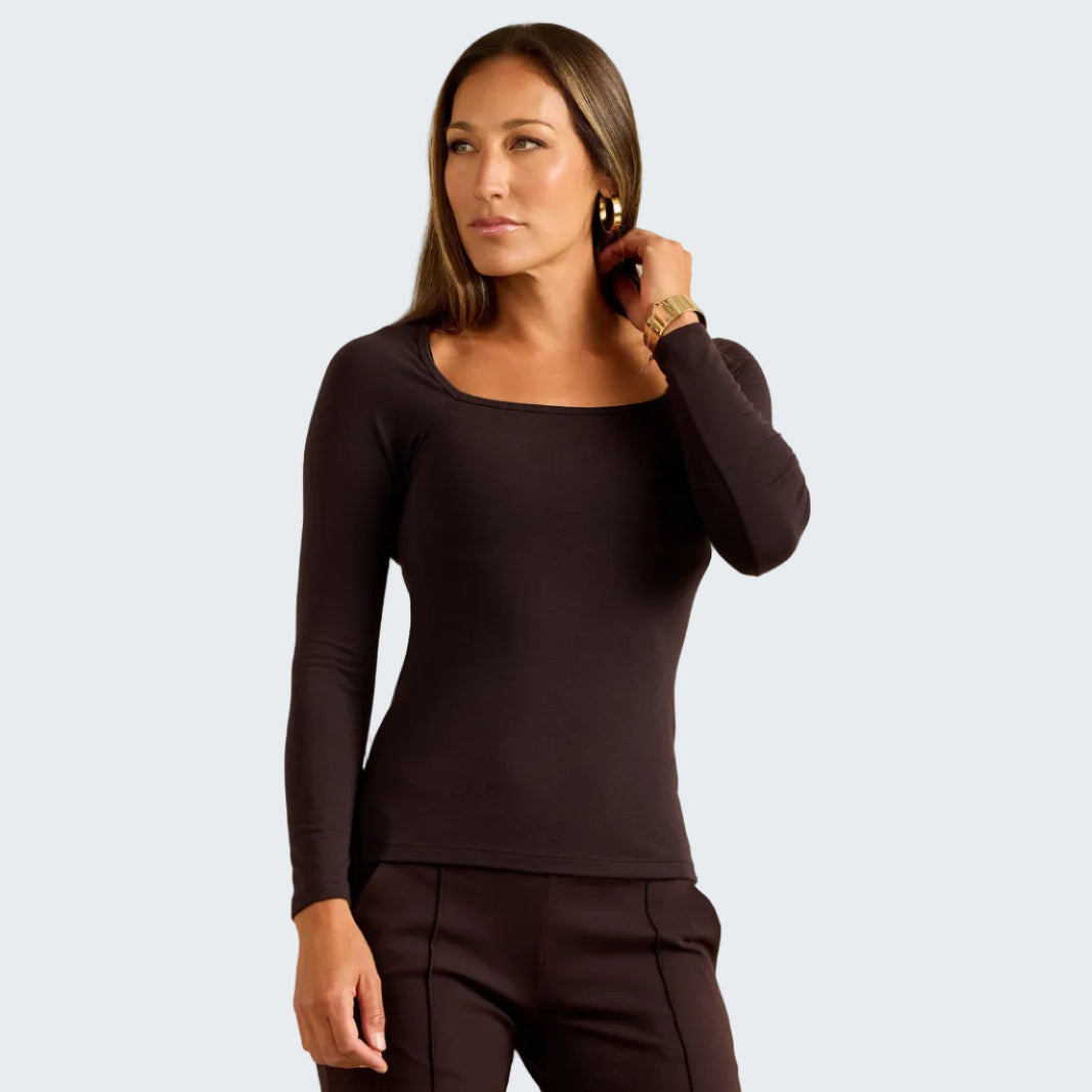 A woman modeling a dark brown long-sleeve scoop-neck top and matching dark brown pants against a textured beige background.