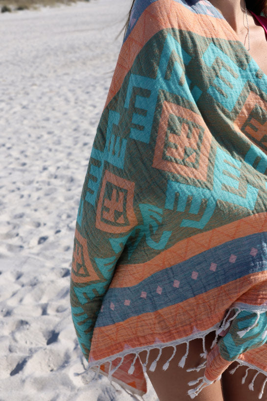 Person holding a patterned towel with geometric designs in an outdoor setting